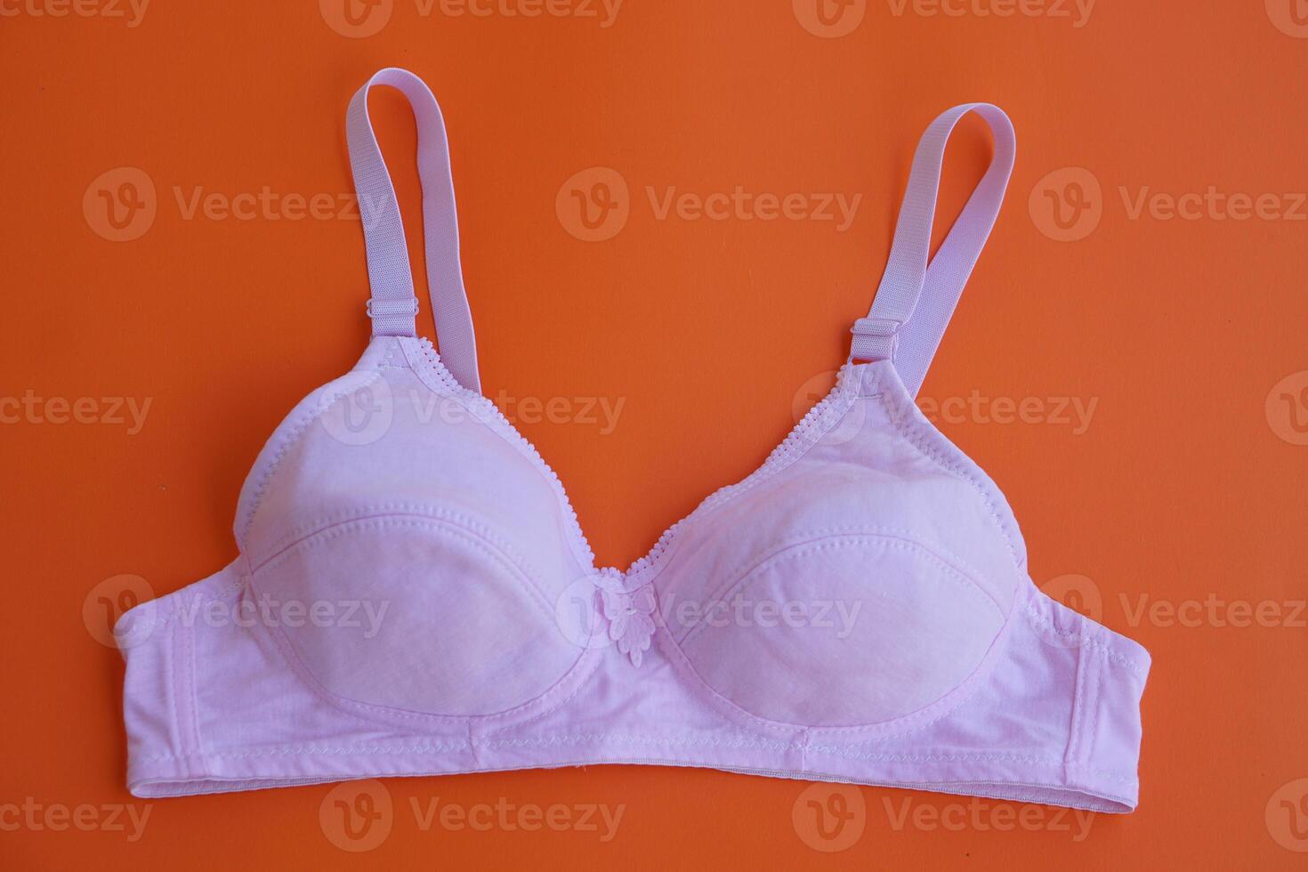 Bra on orange background.Concept, feminine brassiere. Classic comfortable with cup A for female young teenagers. Protect and hold beautiful breasts. Breast cancer awareness. photo