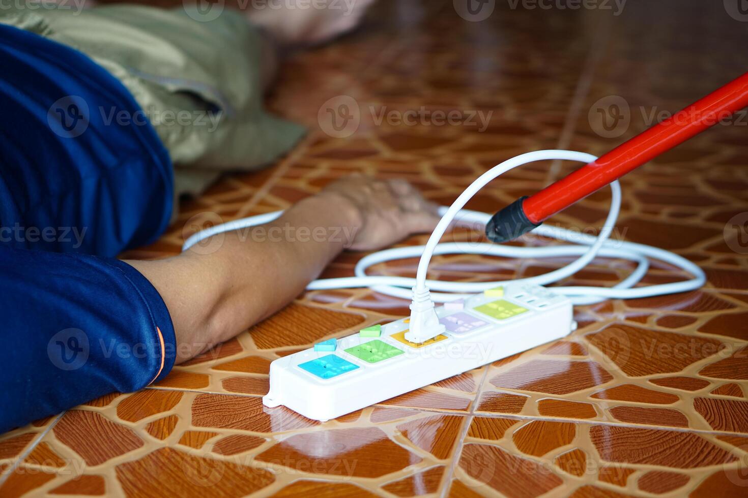 Using red plastic stick is moving away the electric plug socket from the unconscious man who lay down on the floor. Concept, Electric Shock. Emergency basic rescue. First Aid photo