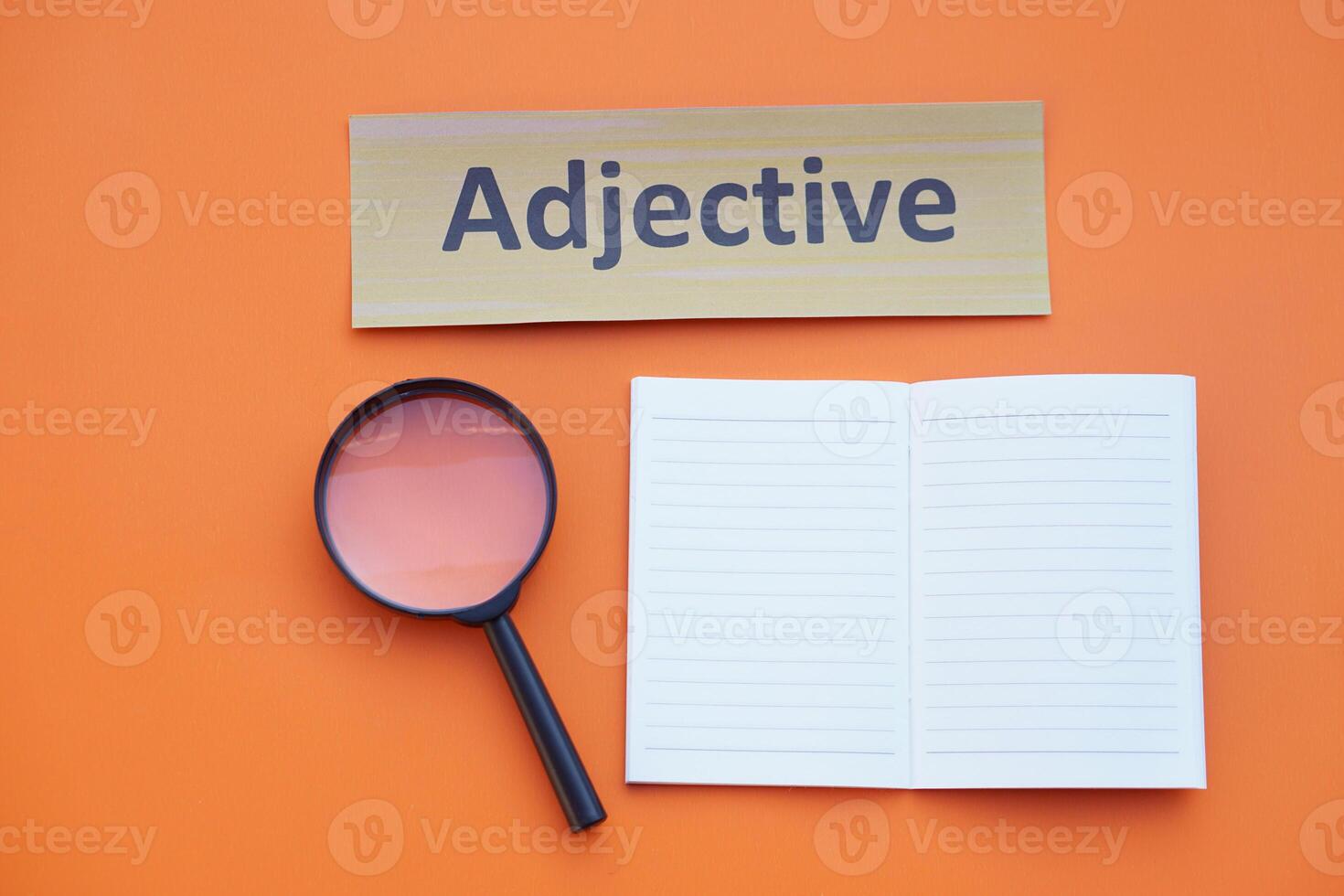 Magnifying glass, paper notebook and Adjective card. Concept. Education material.Teaching aid. Learning language. Find or search adjective words in lesson. photo