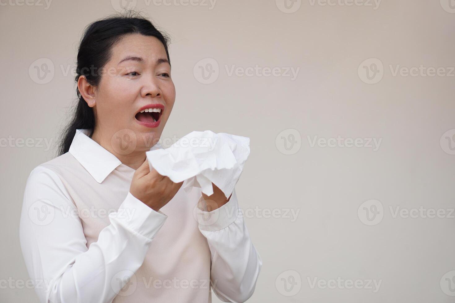 Asian woman is sneezing, open mouth, holds white tissue paper. Concept, Health problems. Ill, sick and flu. Cover mouth when cough or sneeze to stop spreading of germs, disease photo