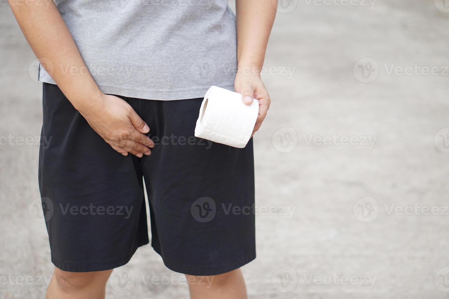 Close up man holds tissue paper roll and crotch , want to go to toilet from cystitis symptom or urinary tract infection. Concept, illness,health problem and health care. photo