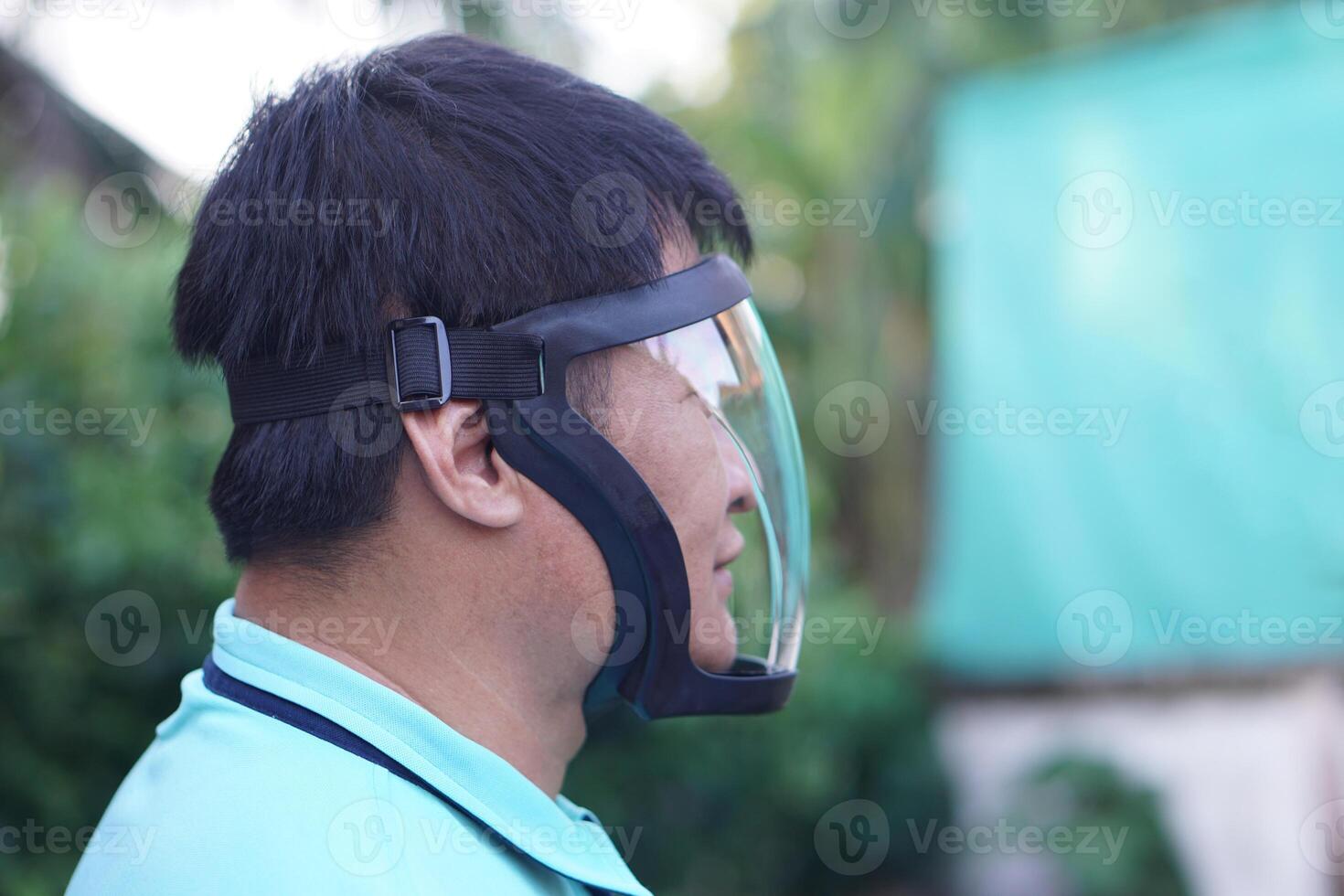 Asian man wears protective safety face shield. Concept, tool, equipment use for wearing with face to protect from dust, germ spreading or others into face. Work Secured helmet shield. photo