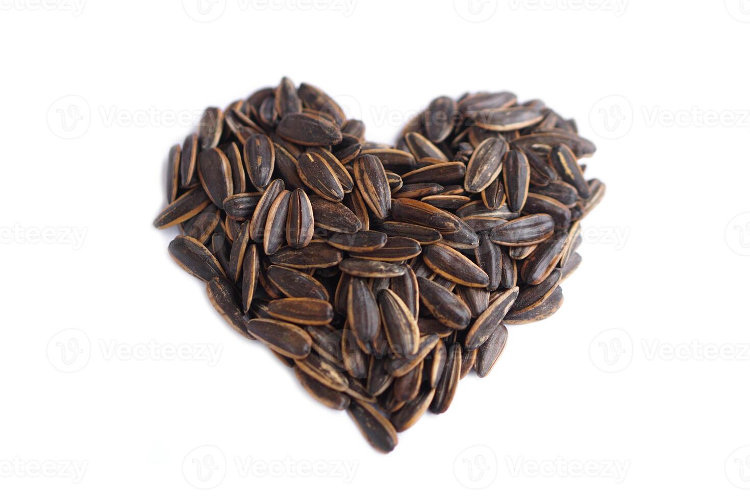 Sunflower seeds, formed in heart shaped, isolated on white background. Concept, agriculture crops. Edible flower seeds as snack or food ingredient. Raw seeds can be grown to expand breed for next time photo