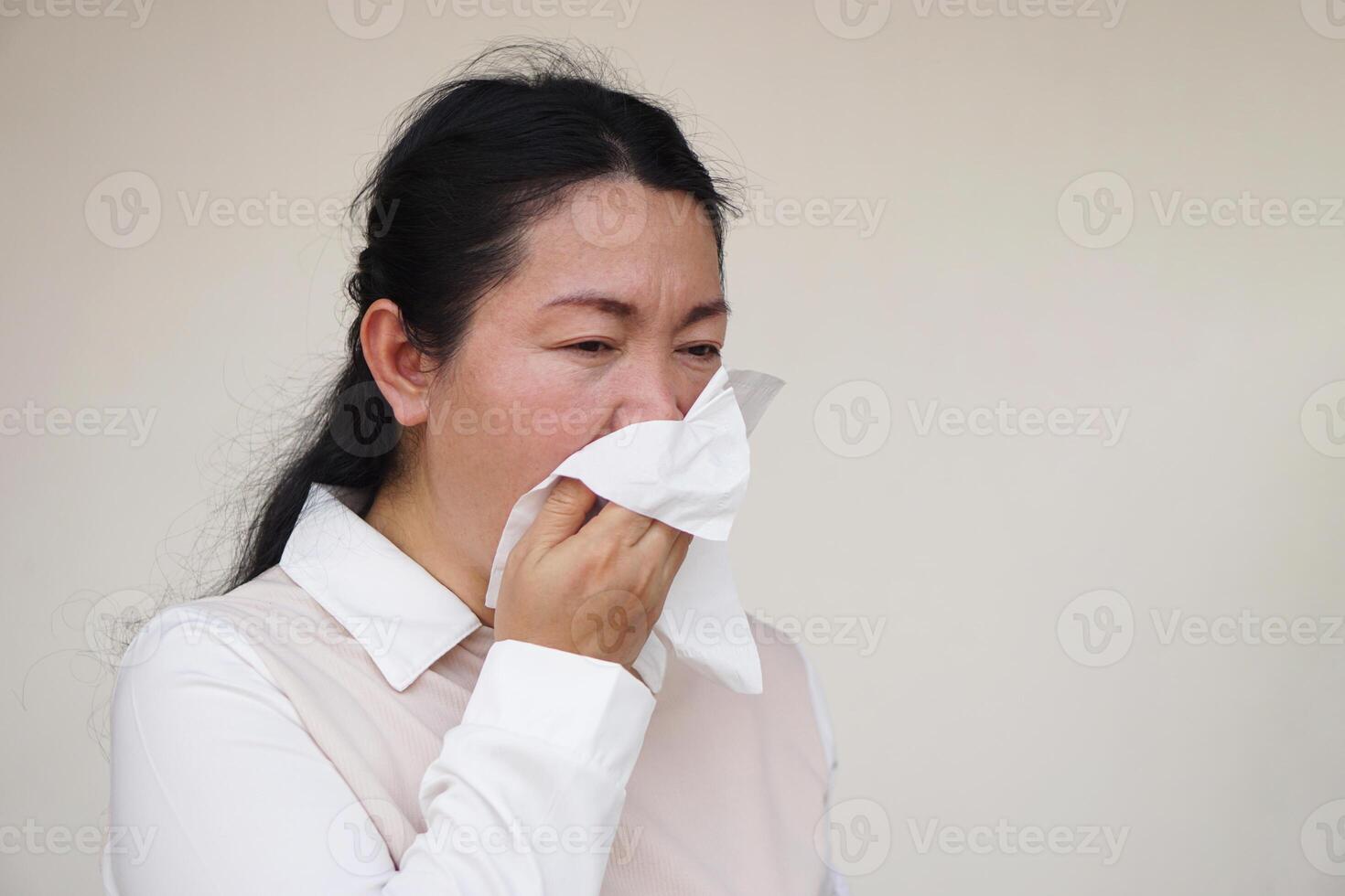 Asian woman hold white tissue paper to cover her mouth or clean runny nose with snot from cold or allergy symptoms. Concept, Health problems. Cover mouth when cough or sneeze to stop spreading of germ photo