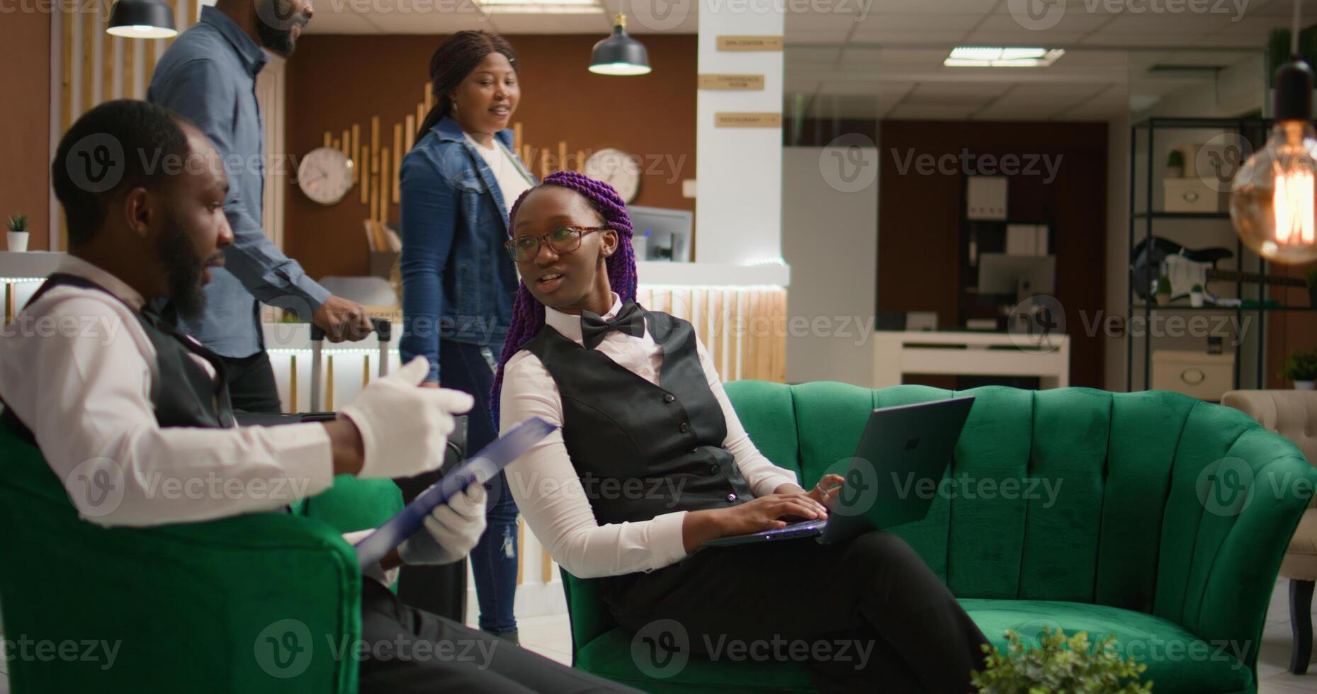 Staff team verifying guests list in lobby, reading personal information on forms to assign clients to rooms. Team of hotel concierge workers managing reservations at luxury resort. photo
