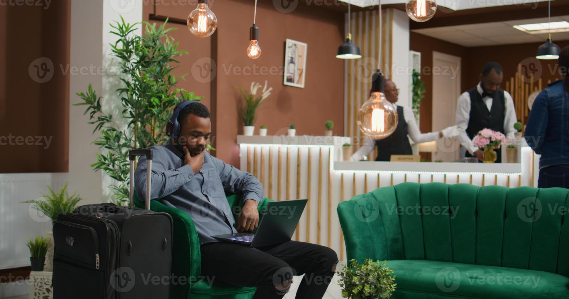Tourist enjoys tv show at holiday resort, waiting for check in procedure before starting vacation and enjoying five star services. Young traveller watching movie in lounge area lobby. photo
