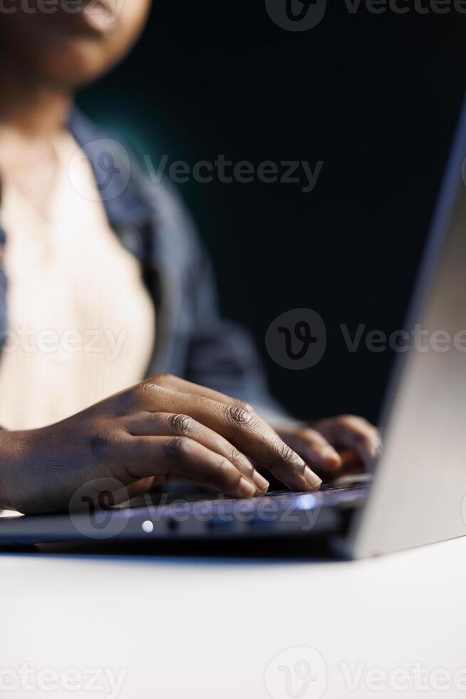 Black woman working on digital laptop, typing and replying emails, browsing online. Detailed view of african american female communicating and utilizing technology as a freelancer. photo