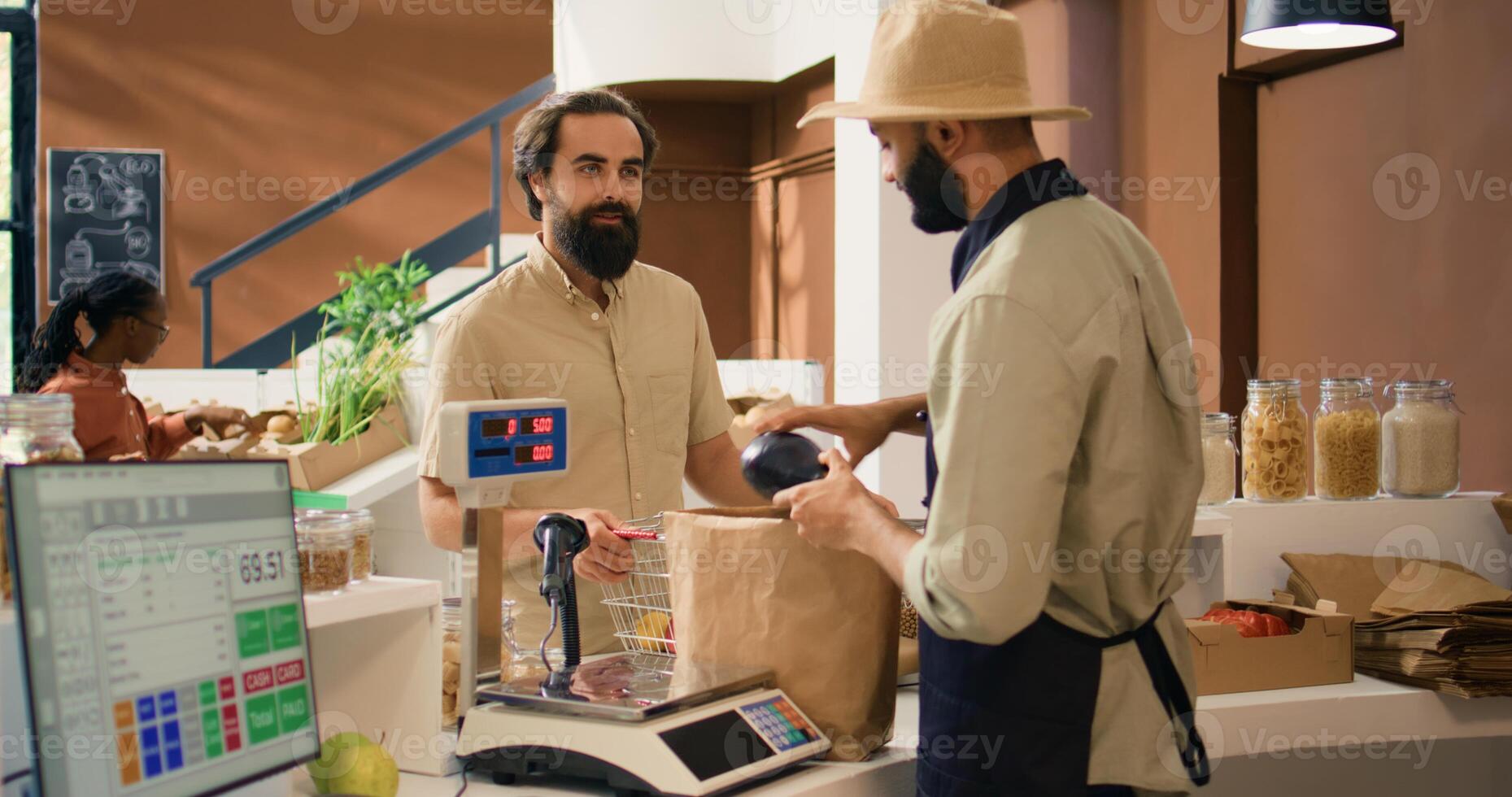 Store owner serving client with produce after weighting ripe fruits and vegetables on scale, putting organic products in paper bag. Young buyer supporting sustainable lifestyle and farming. photo