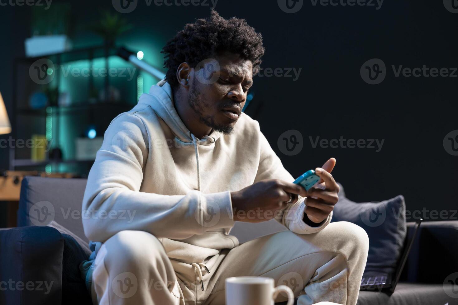 BIPOC man using pulse oximeter to monitor level of blood oxygen saturation and heart rate, doing annual checkup in cozy apartment living room as recommended by his doctor photo