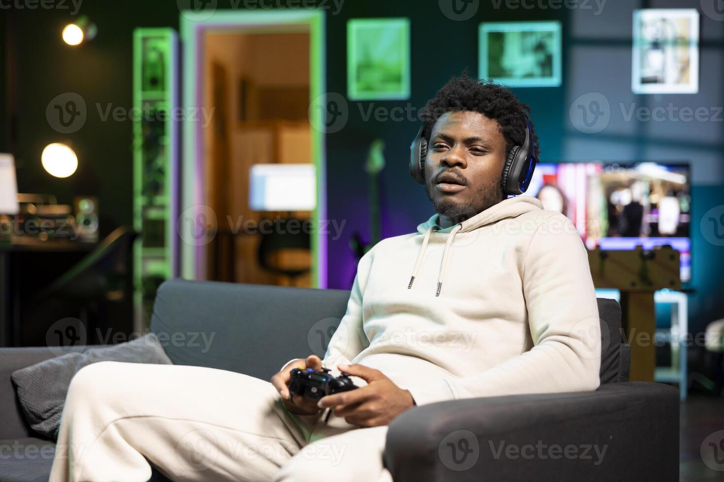 BIPOC gamer at home sitting down on couch, enjoying games on laptop during leisure time. Man sitting on couch in apartment, playing videogame on notebook, relaxing after work photo