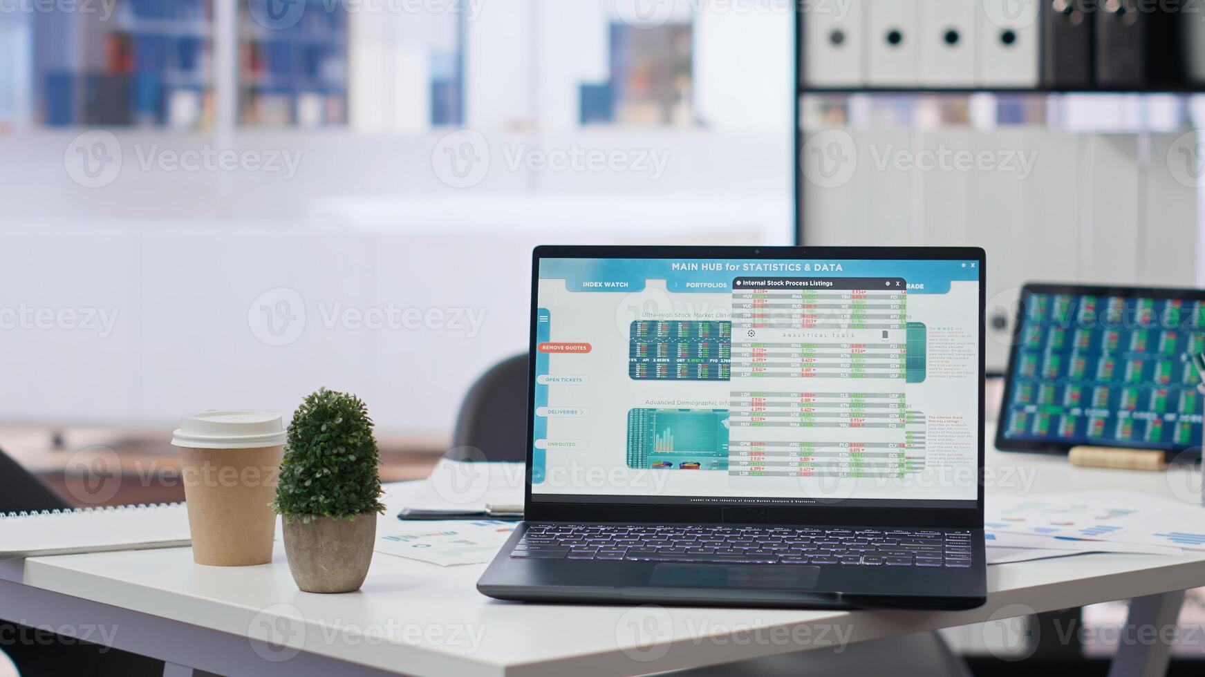 Financial analyst workplace featuring laptop and tablet displaying stock exchange data and statistics. Close up shot of devices on desk next to paperwork with forex trading economic analytics figures photo