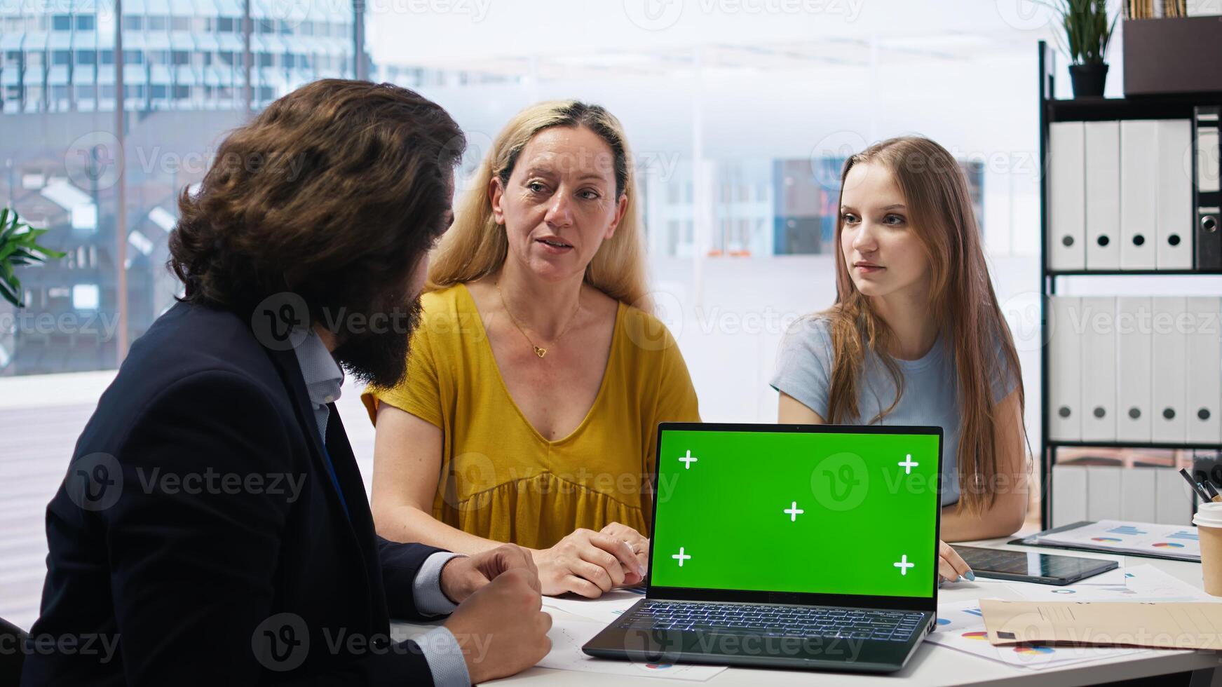 Family receiving personalized financial plan from financial advisor using green screen laptop during meeting. Clients learn how to make profitable decisions from agent using mockup notebook, camera A photo