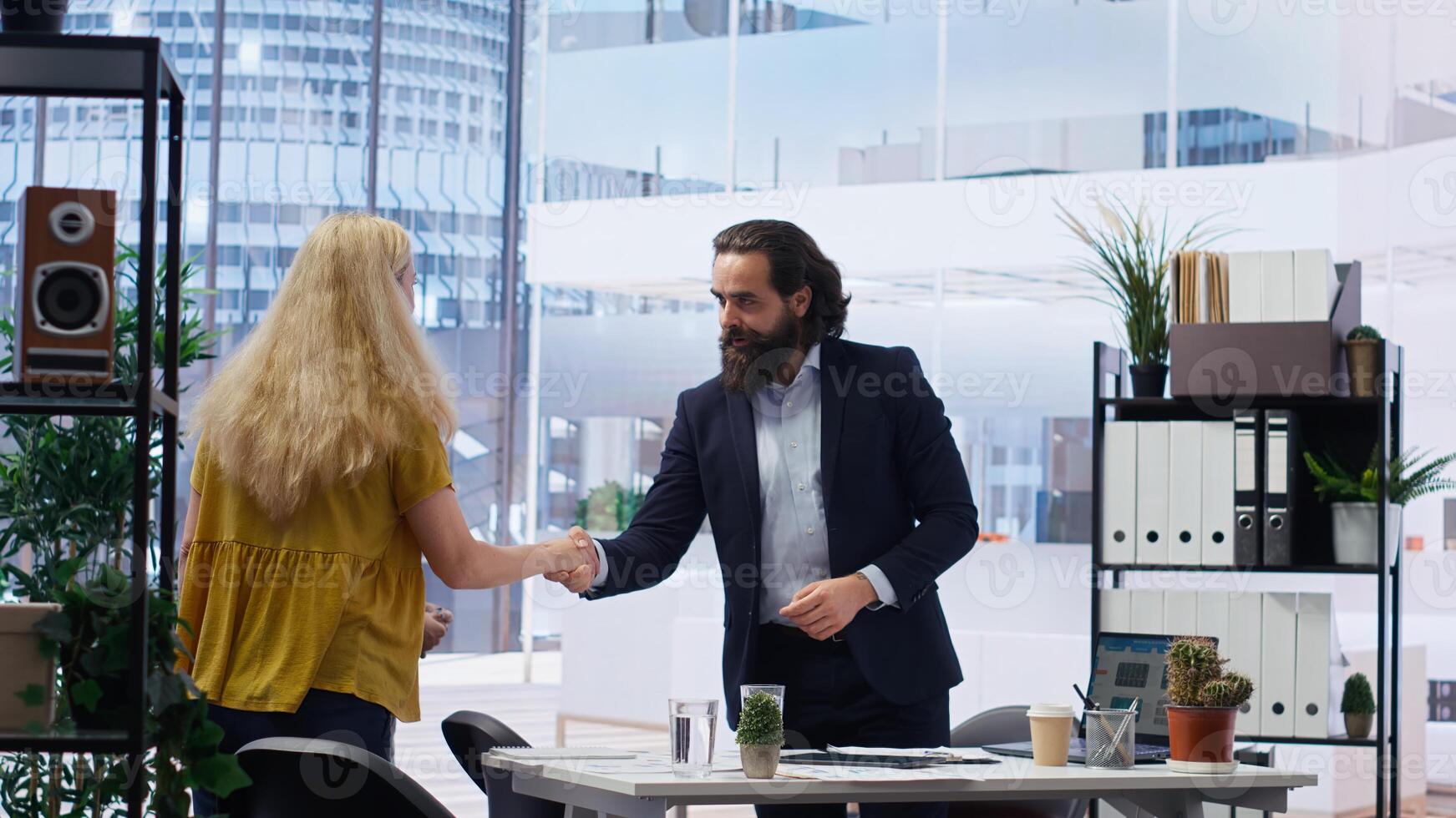 Portrait of cheerful financial advisor in office meeting with parent and child to provide personalized spending planning. Jolly agent in workspace doing handshake with customers, camera B photo