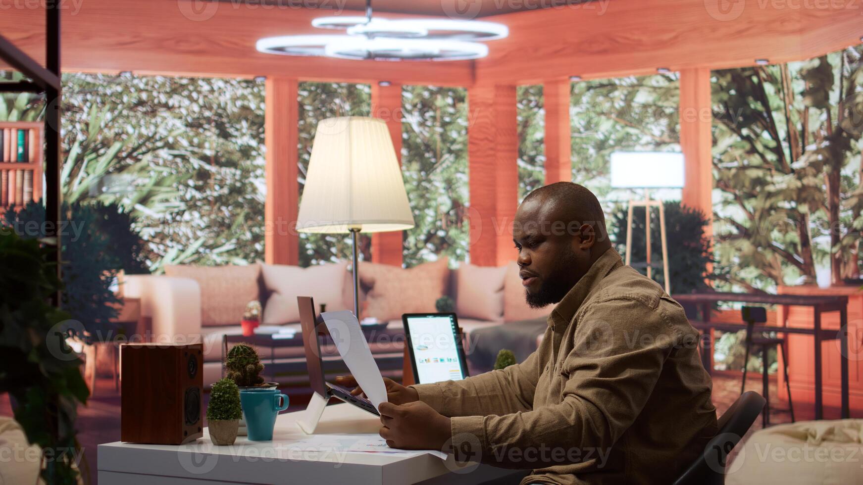 Startup entrepreneur calculating the annual sales reports to review the budget, working to develop the business activity. Businessman analyzing profit and expenses on his laptop at home. Camera B. photo