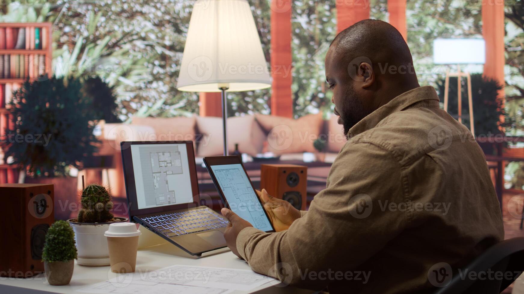 Businessman searching for commercial office spaces from his home workstation, doing a blueprints review and drafting building layouts to find the perfect startup property. Real estate. Camera B. photo