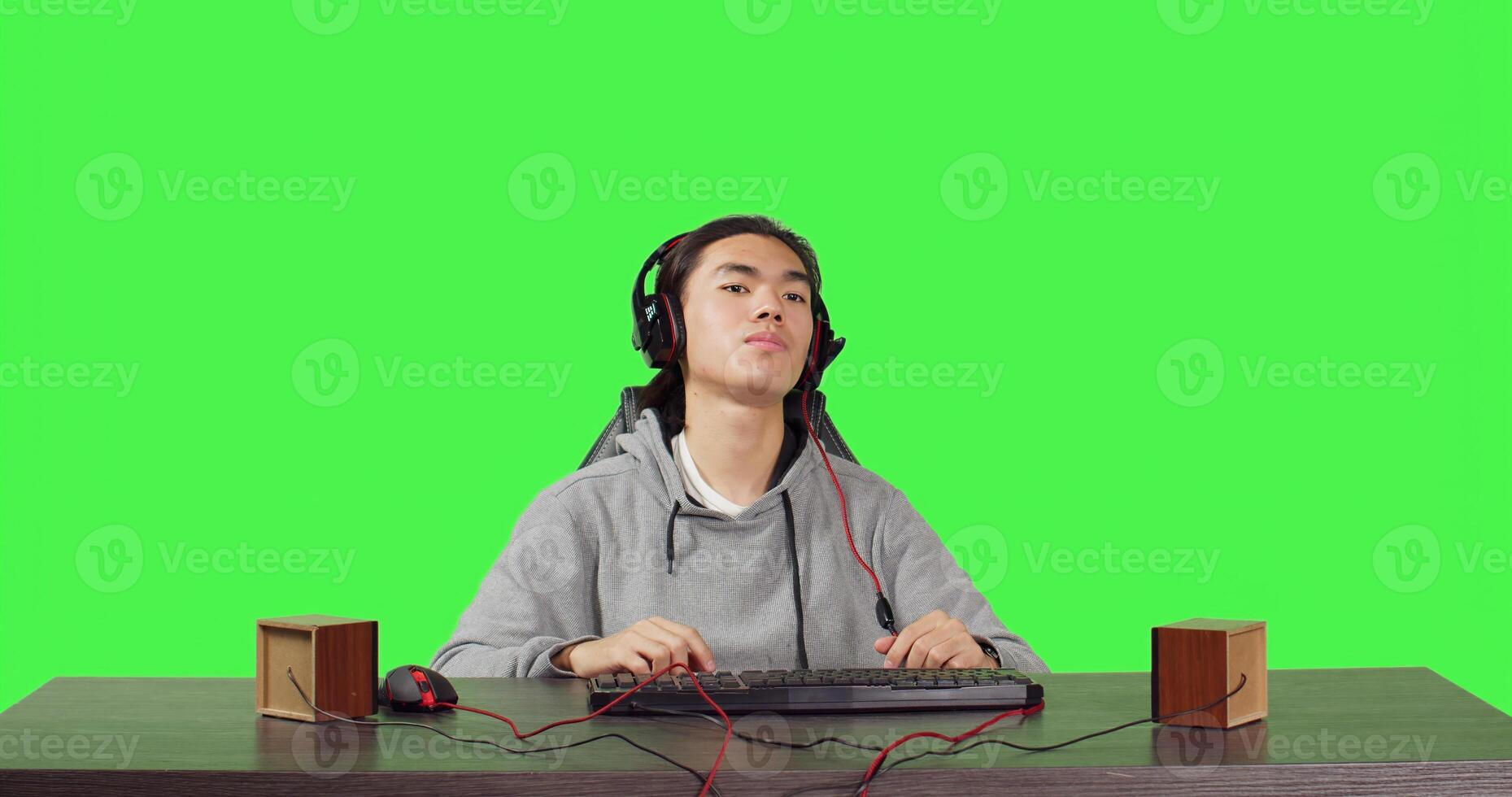 POV of person plays pc videogames at workstation, sitting on office chair over greenscreen. Modern guy having fun online with colleagues in rpg competition, wearing headset at his desk. photo
