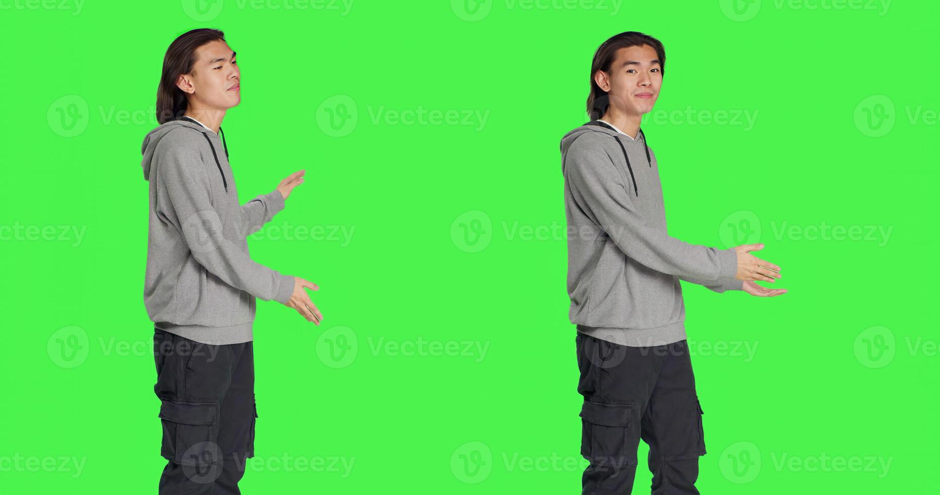 Male model creating advertisement showing something to left or right sides in studio, pointing at thing over greenscreen background. Young guy advertising slogan for marketing industry. photo