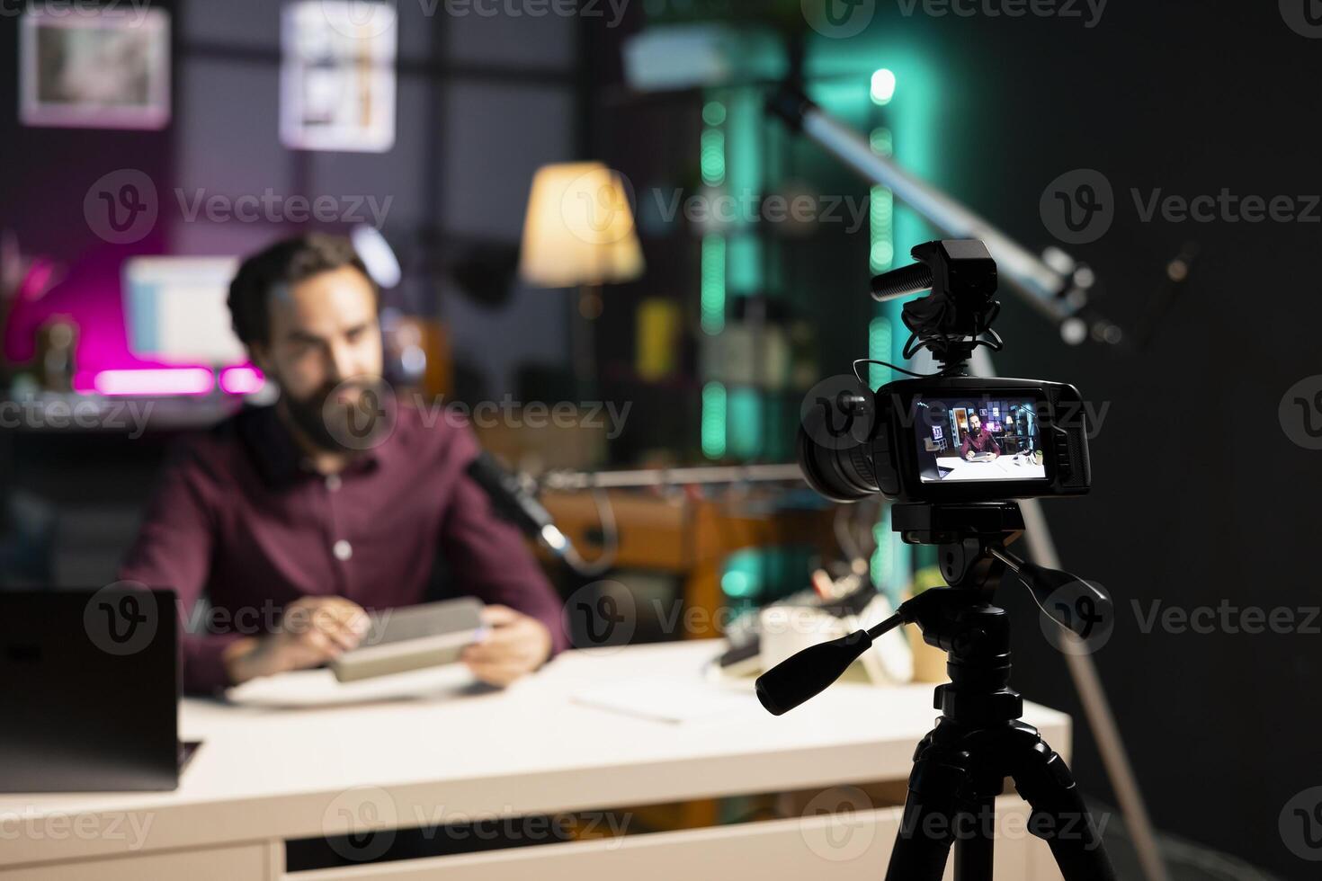 Focus on tech guru in blurry background doing technology review of wireless portable speaker. Close up shot of professional camera used by influencer to record music playing device review photo