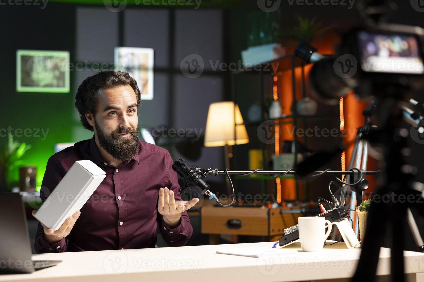 Tech influencer using professional camera and mic to film technology review of smartphone, doing unboxing . Man showing phone box to viewers, recording with high tech devices photo