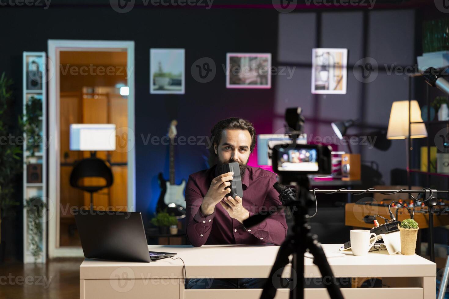 Tech expert paid by sponsor to endorse portable V mount battery, filming with professional camera in studio. Man contracted by company to advertise lithium li-ion charging device to audience photo