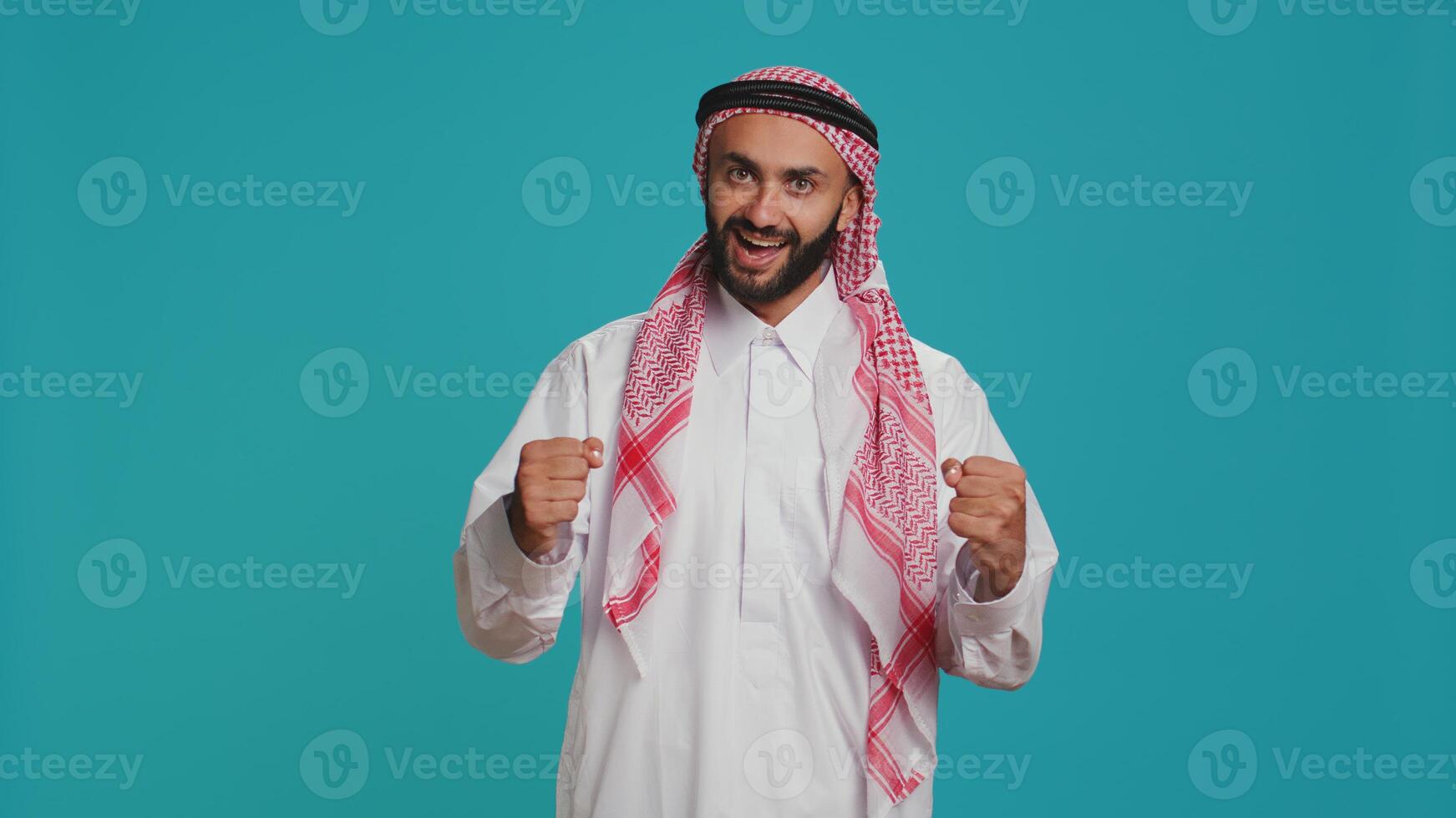 Modern guy cheering and showing his support in front of camera, feeling optimistic and joyful about something. Middle eastern person being brave and giving strength with cheers. photo