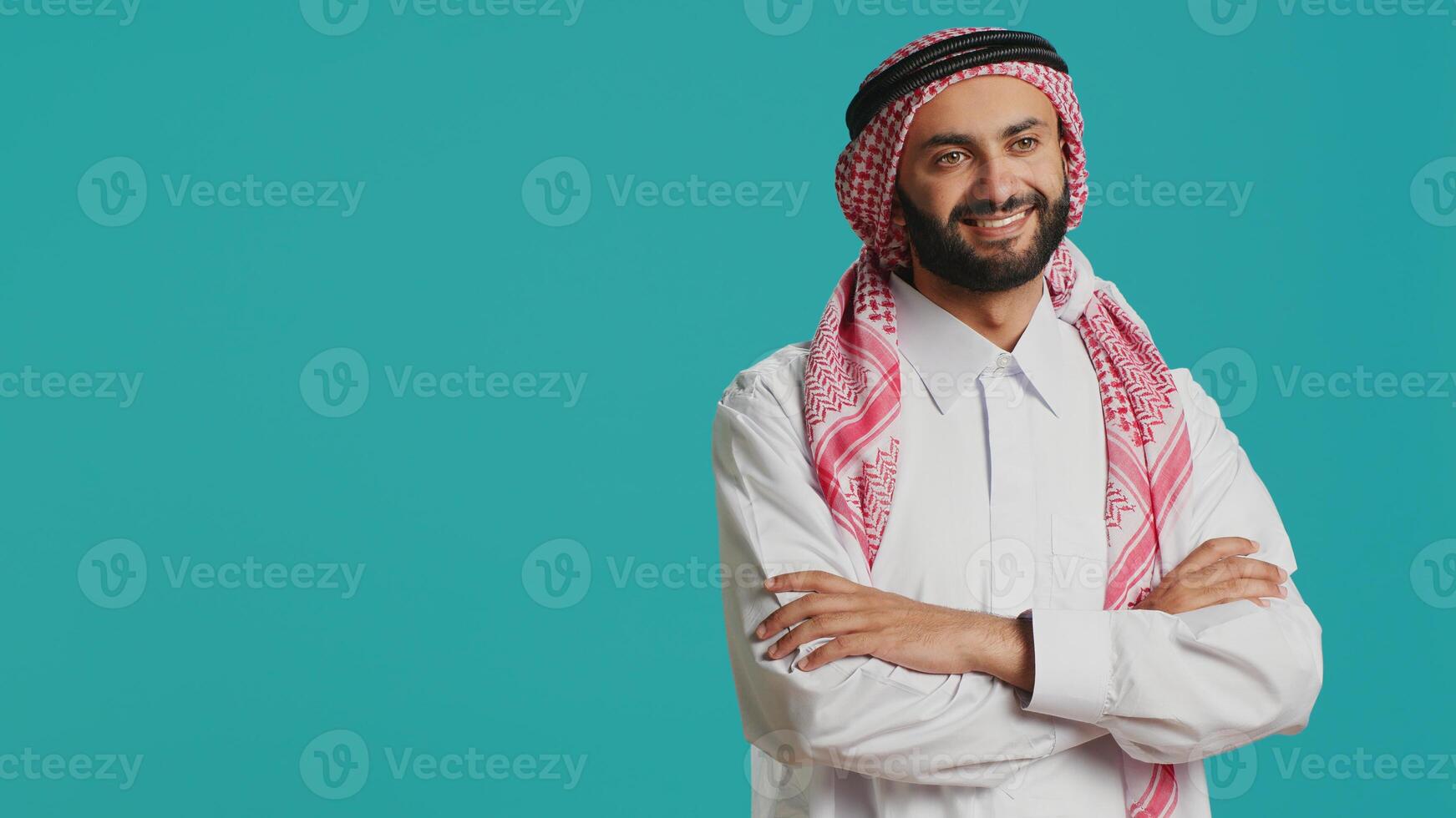Adult in traditional thobe and kufiyah appears delighted, representing authentic muslim beliefs and practices. Cultural identity of middle eastern man attired in loincloth and patterned scarf. photo