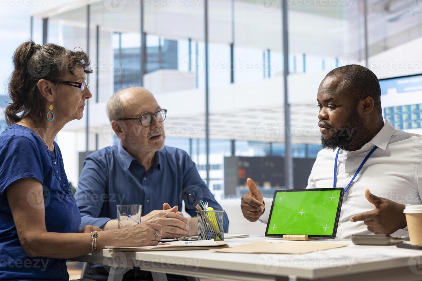 Financial banker works with a copy space on tablet with his elderly clients, showcasing retirement plans and pension options to secure their income and life savings. Insurance agency. photo