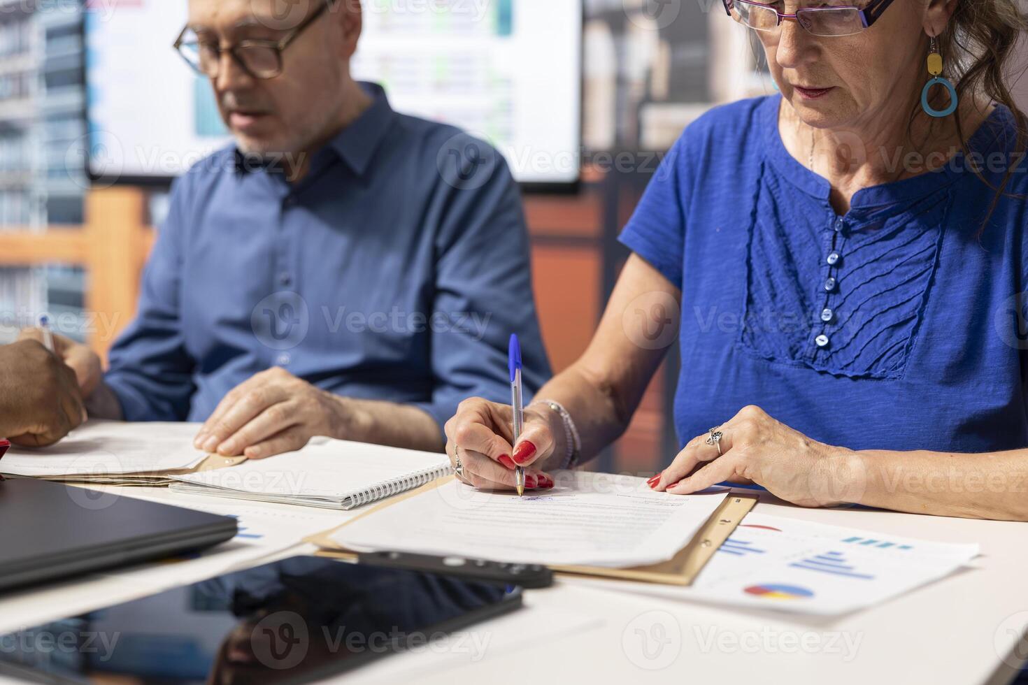 Senior couple signing the contract for a pension plan in a meeting with banker, agreeing on the perfect retirement option package to benefit from, financial stability and security. photo