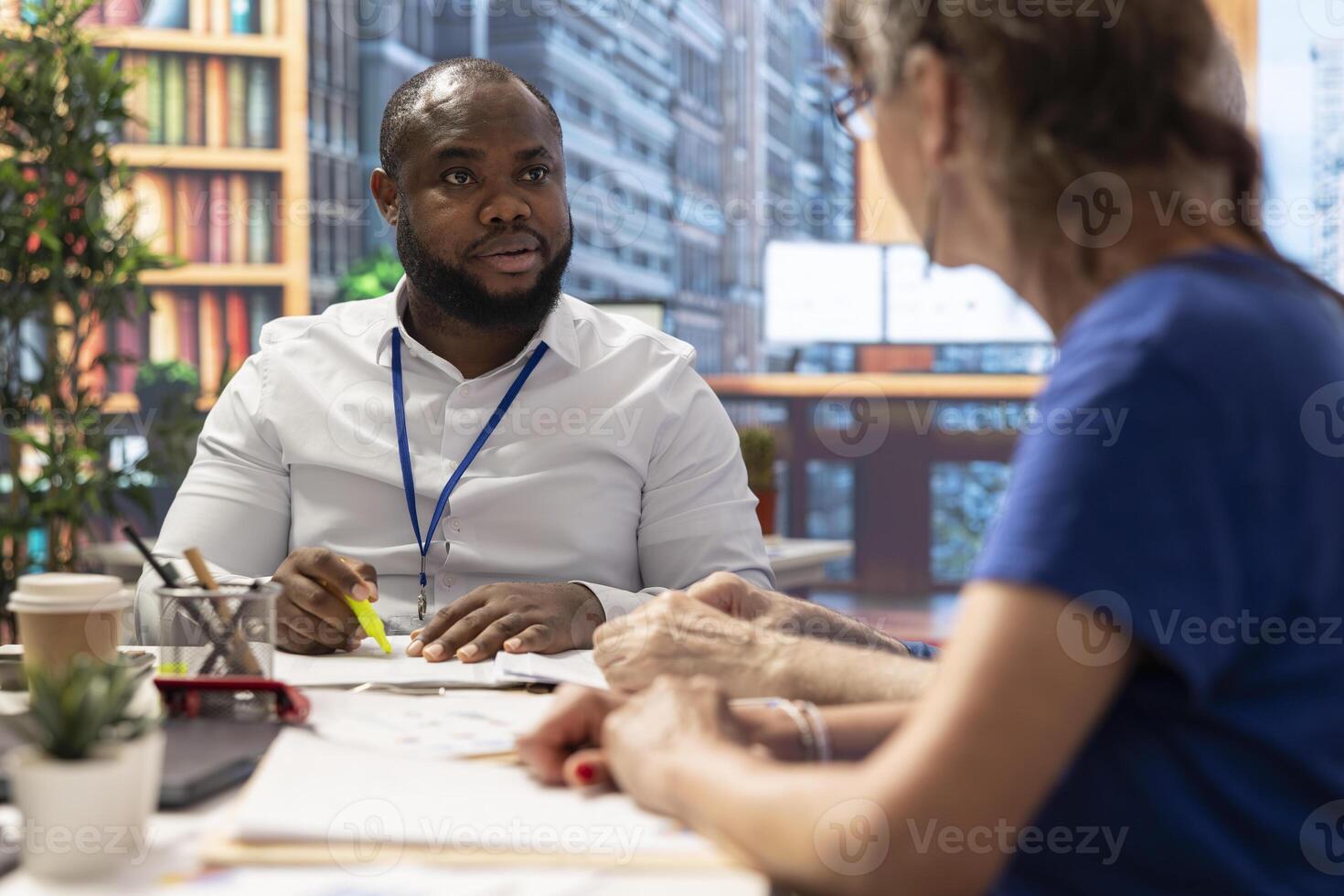 Broker expert highlighting important terms from the contract and explaining the insurance agency policy to senior clients. Offering professional advice to elderly man and woman in modern office. photo