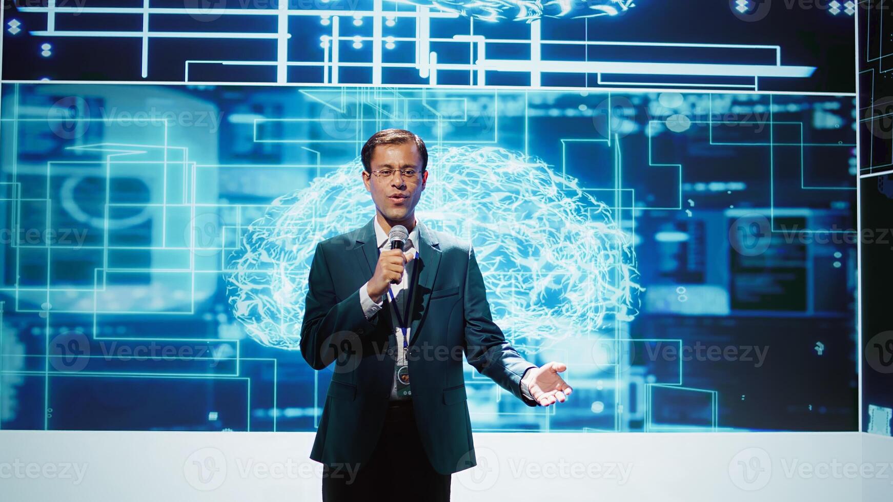 Upbeat presenter inviting engineer on stage during global IT conference to talk about subjects such as enterprise AI, deep learning, big data, neural networks and cognitive computing, camera B photo