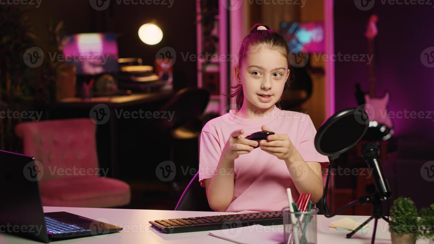 Kid content creator filming keyboard review in home studio, pressing different buttons to show typing capabilities. Little girl showcasing computer peripherals to audience on gen Z online channel photo