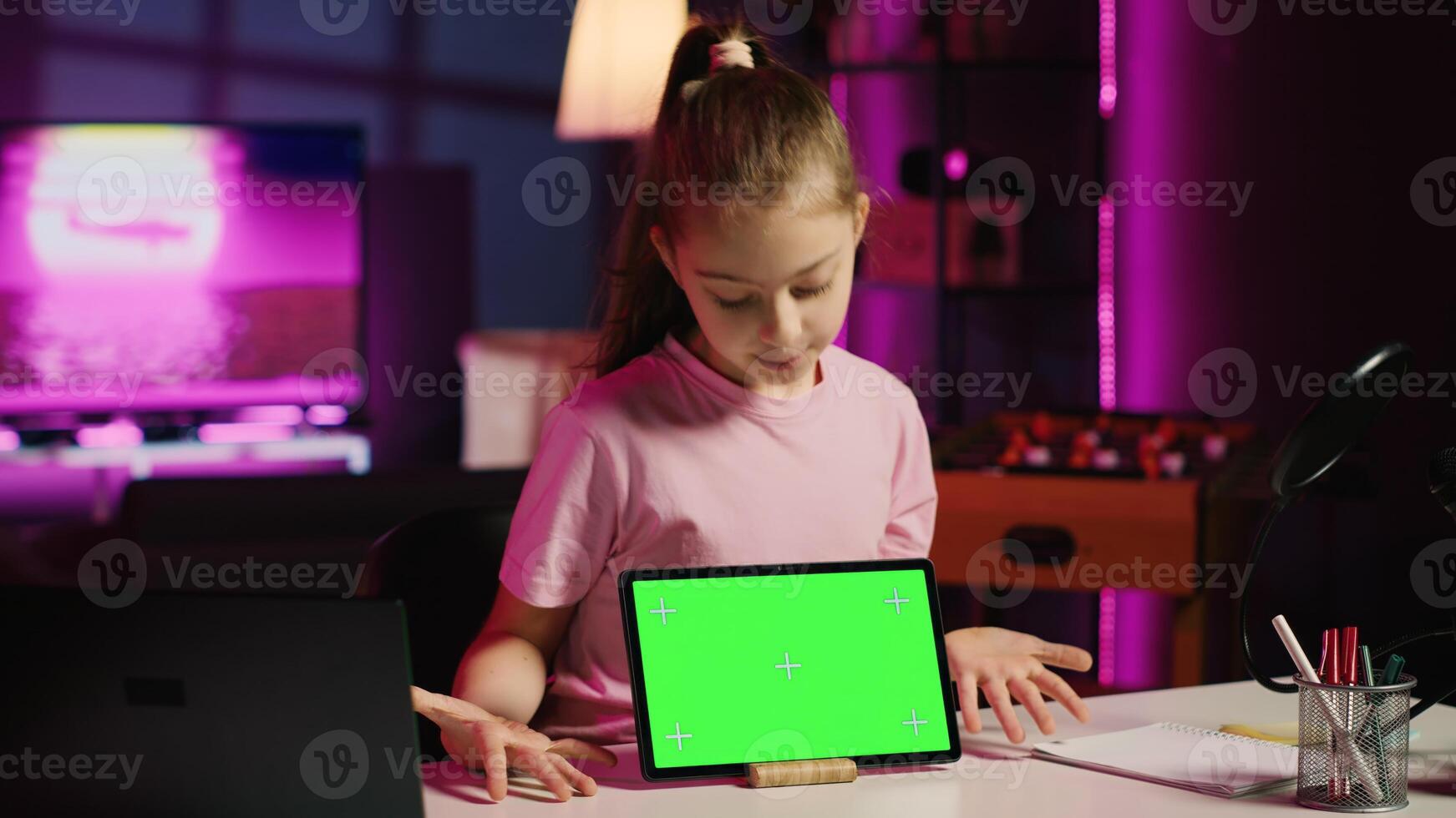 Cute child content creator filming technology review of newly released isolated screen tablet, unpacking it and presenting specifications to audience. Young online star showing mockup device to fans photo