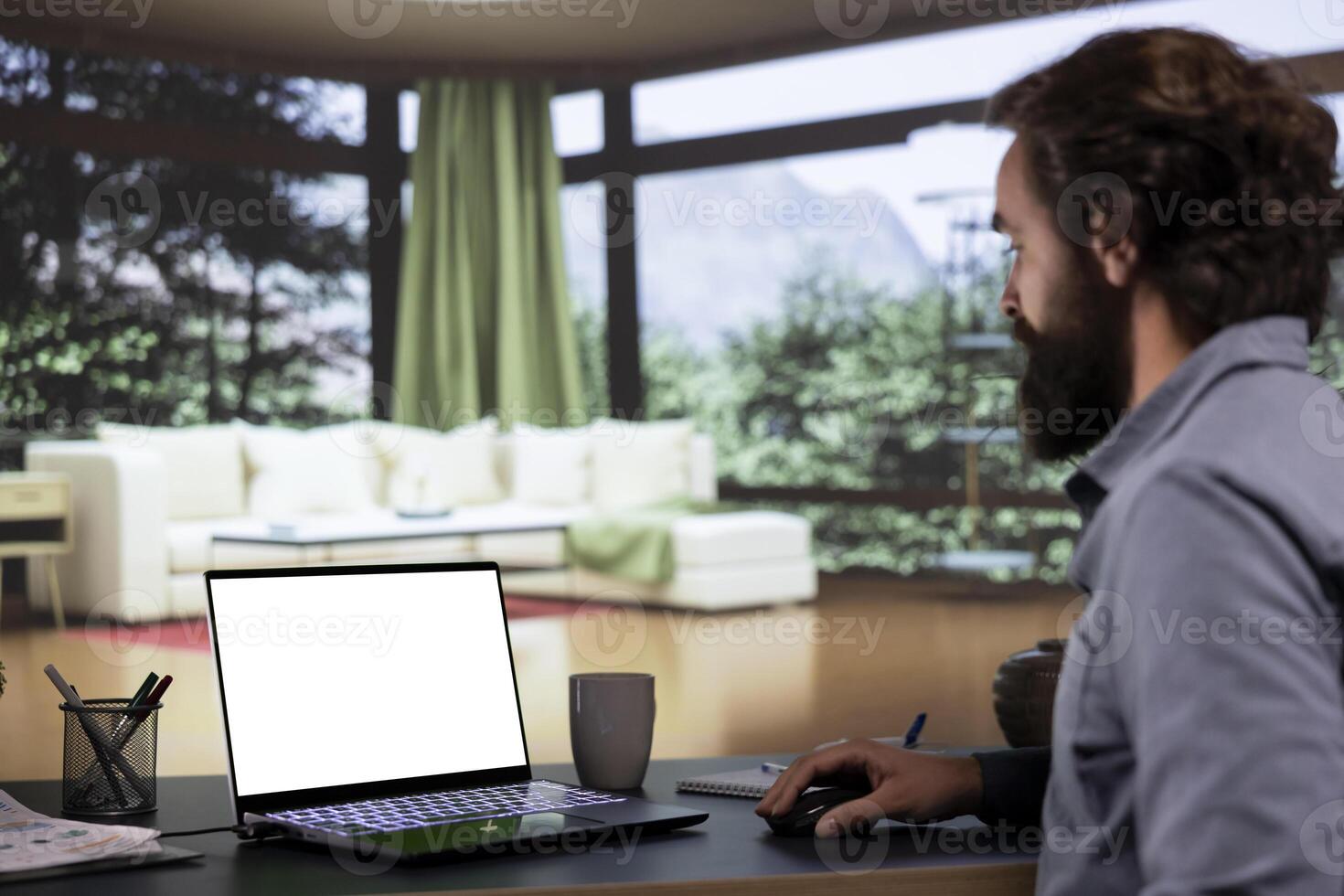 Business owner uses laptop to check white screen at home, relaxing at his luxurious vacation villa. Wealthy chief executive director looking at blank mockup display on laptop, global enterprise. photo