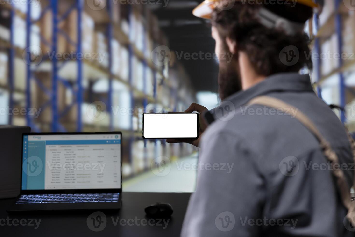 Storage room engineer using smartphone with white display, reading cargo details on distribution contracts. Supervisor with helmet looking at phone with blank mockup layout, warehouse logistics. photo