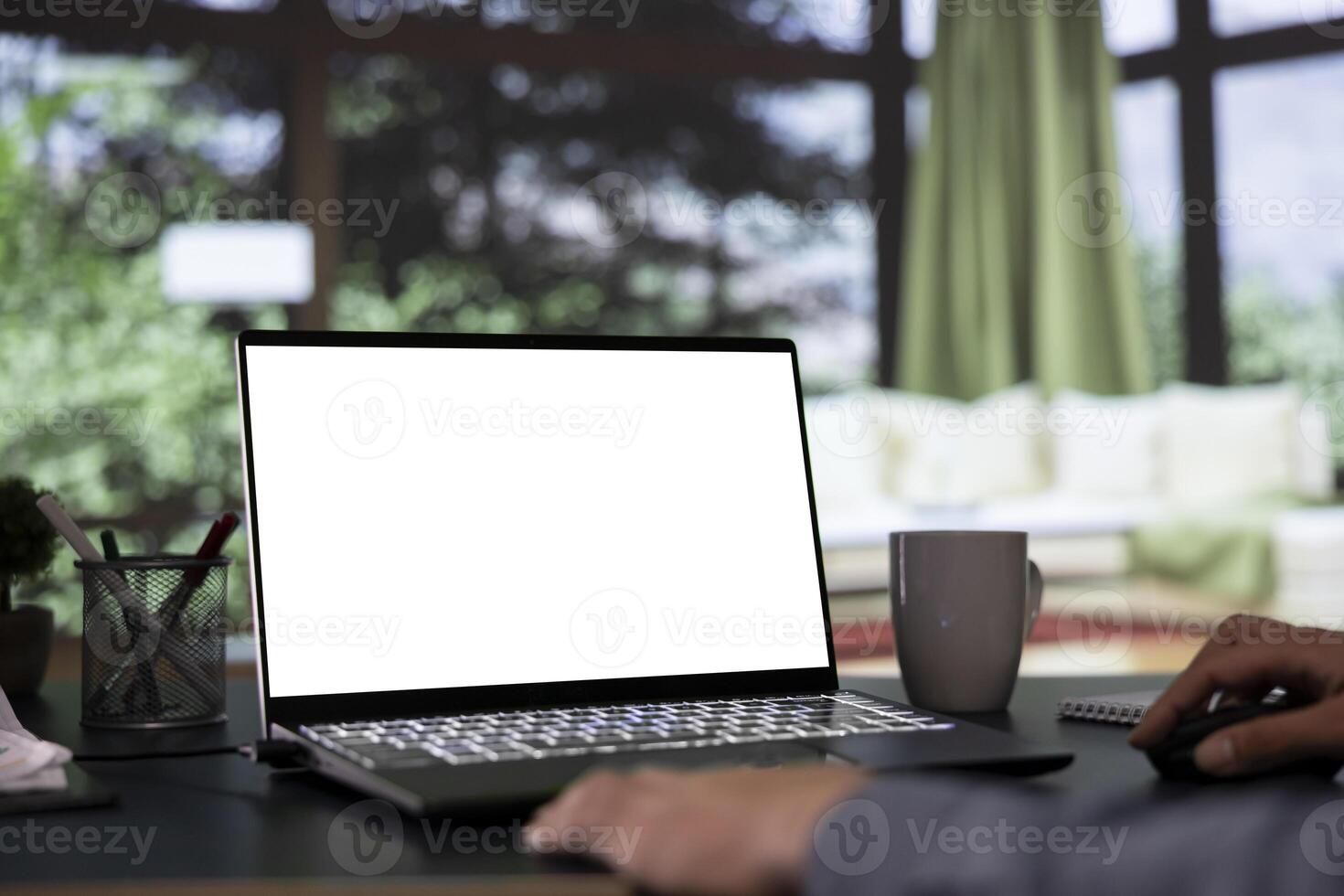 Billionaire director unwinds in front of white display on laptop, luxurious mountain cabin. In a successful business corporation, general manager operates with blank mockup screen on pc. photo