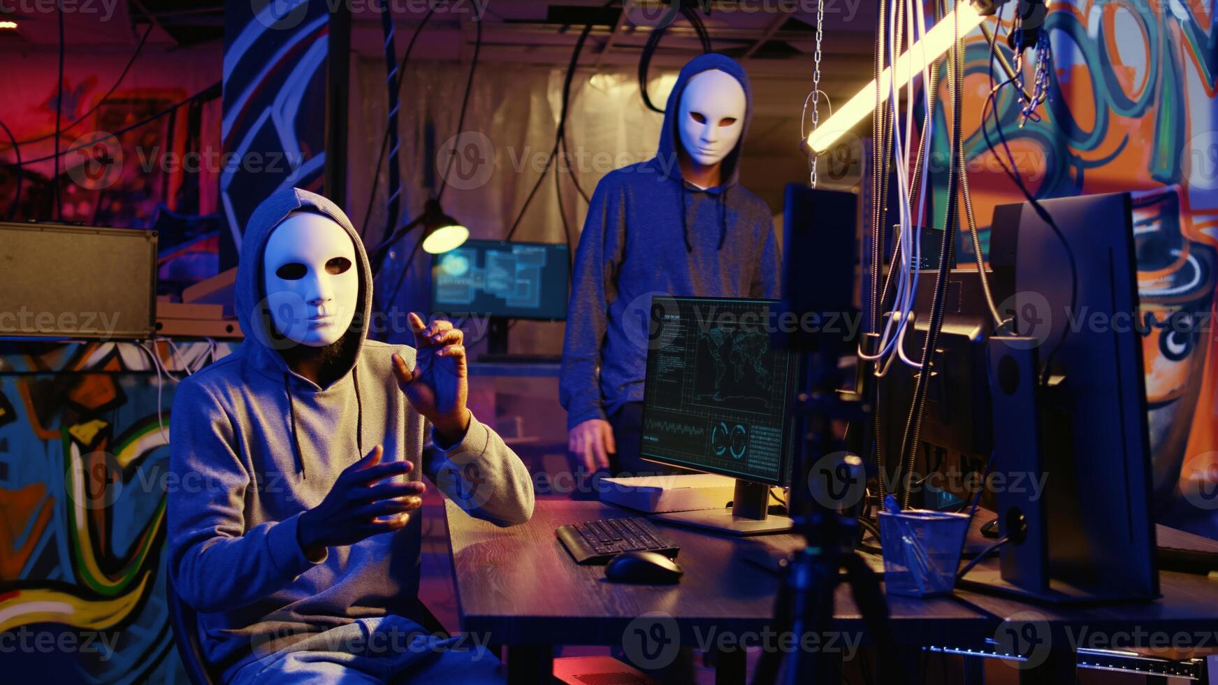 Hacker group wearing anonymous masks filming threatening another country government to steal military secrets, doing international espionage in hidden underground base photo