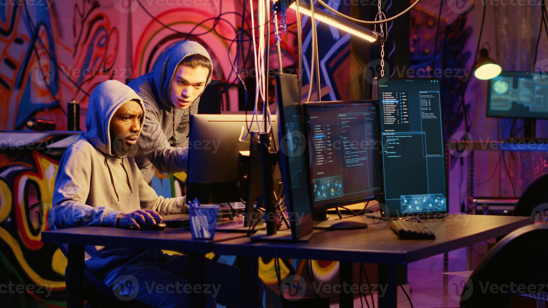 Beginner hacker requesting help from experienced cybercriminal, learning how to destroy firewalls and infect victim computer. Cracker in secret hideout teaches script kiddie how to write malware code photo