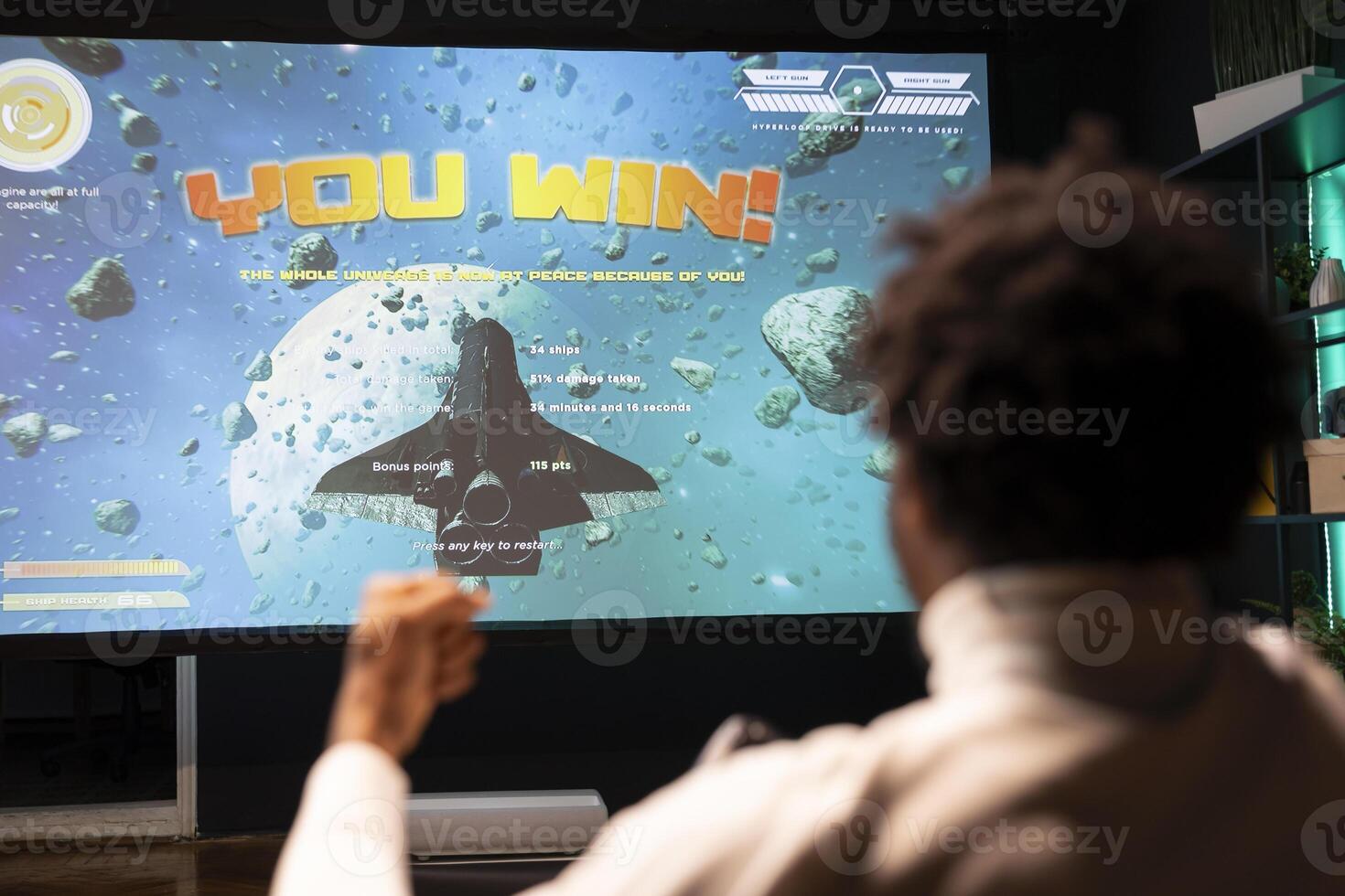African american man playing videogames on gaming console, celebrating victory. Gamer excited after winning online multiplayer game match on ultrawide smart TV display, rejoicing photo