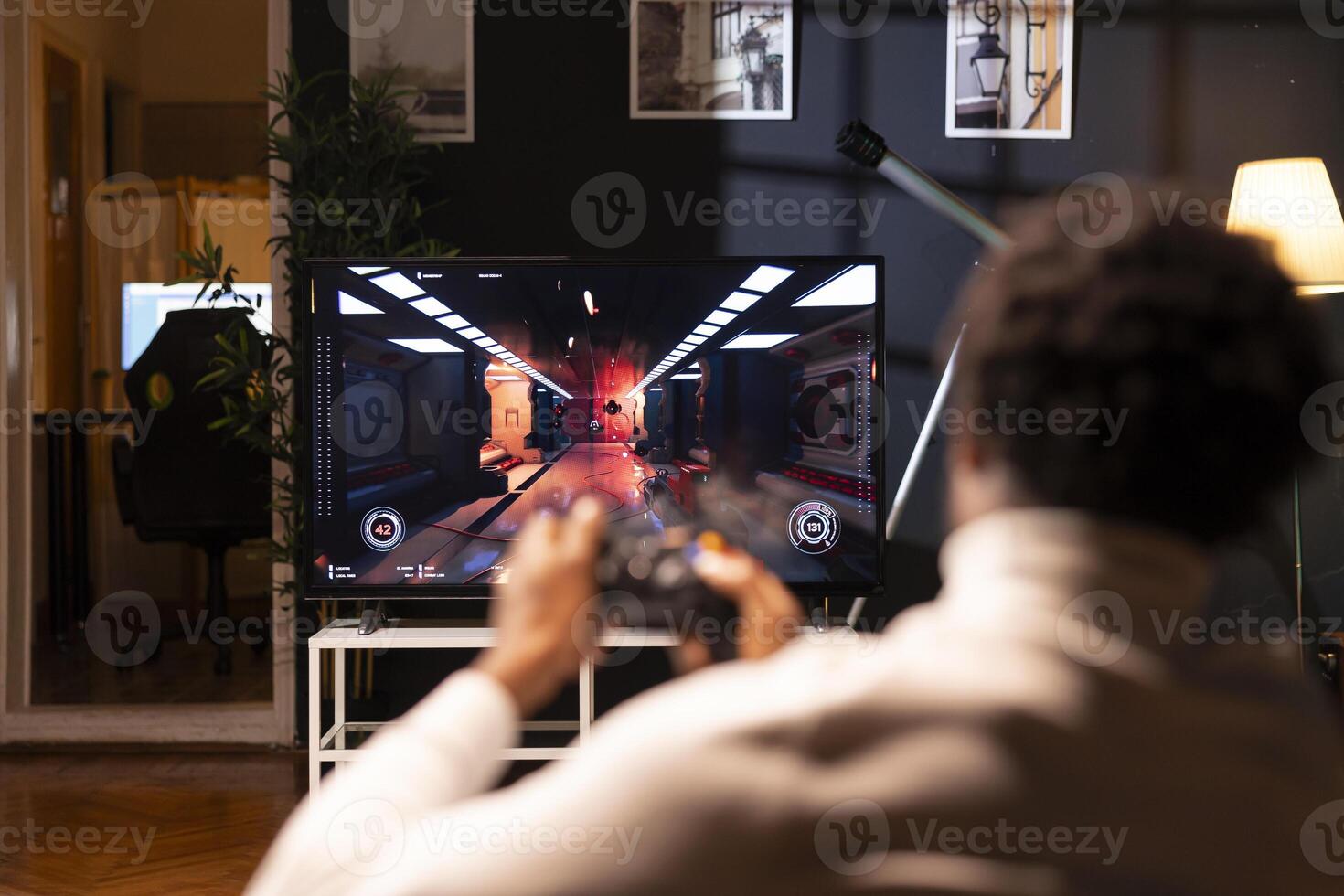 Player using controller to play first person shooter videogame on smart TV, enjoying leisure time. Man in home theatre using high tech gaming console joystick to destroy flying robots photo