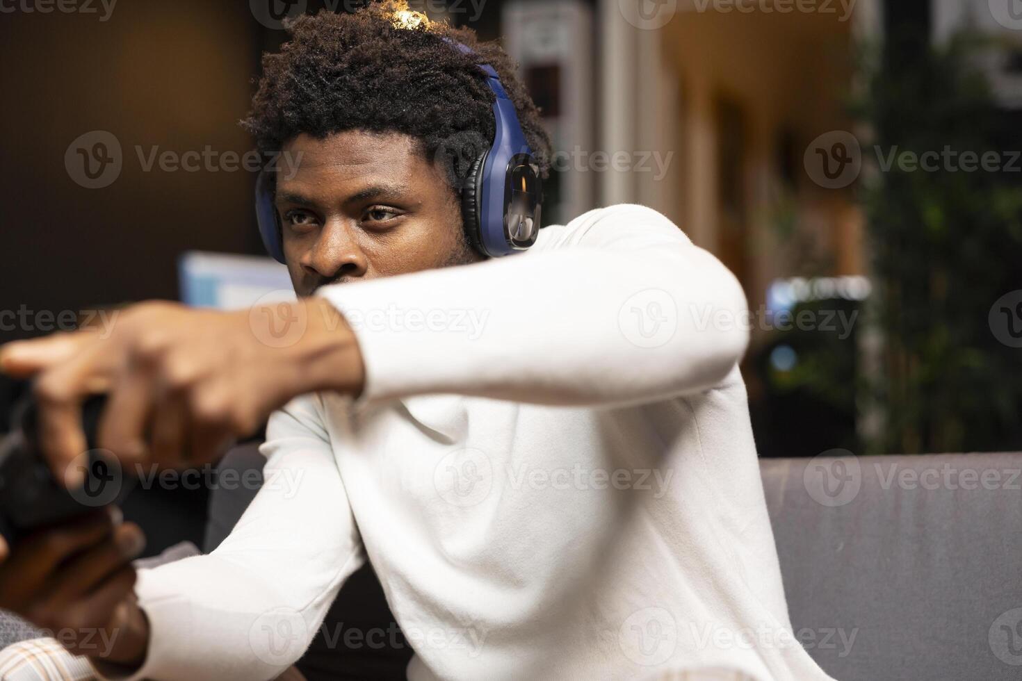 African american man focused on defeating enemies while playing videogames on gaming console with teammates. Player fights foes in esports game using gamepad, chatting with friends through headset photo