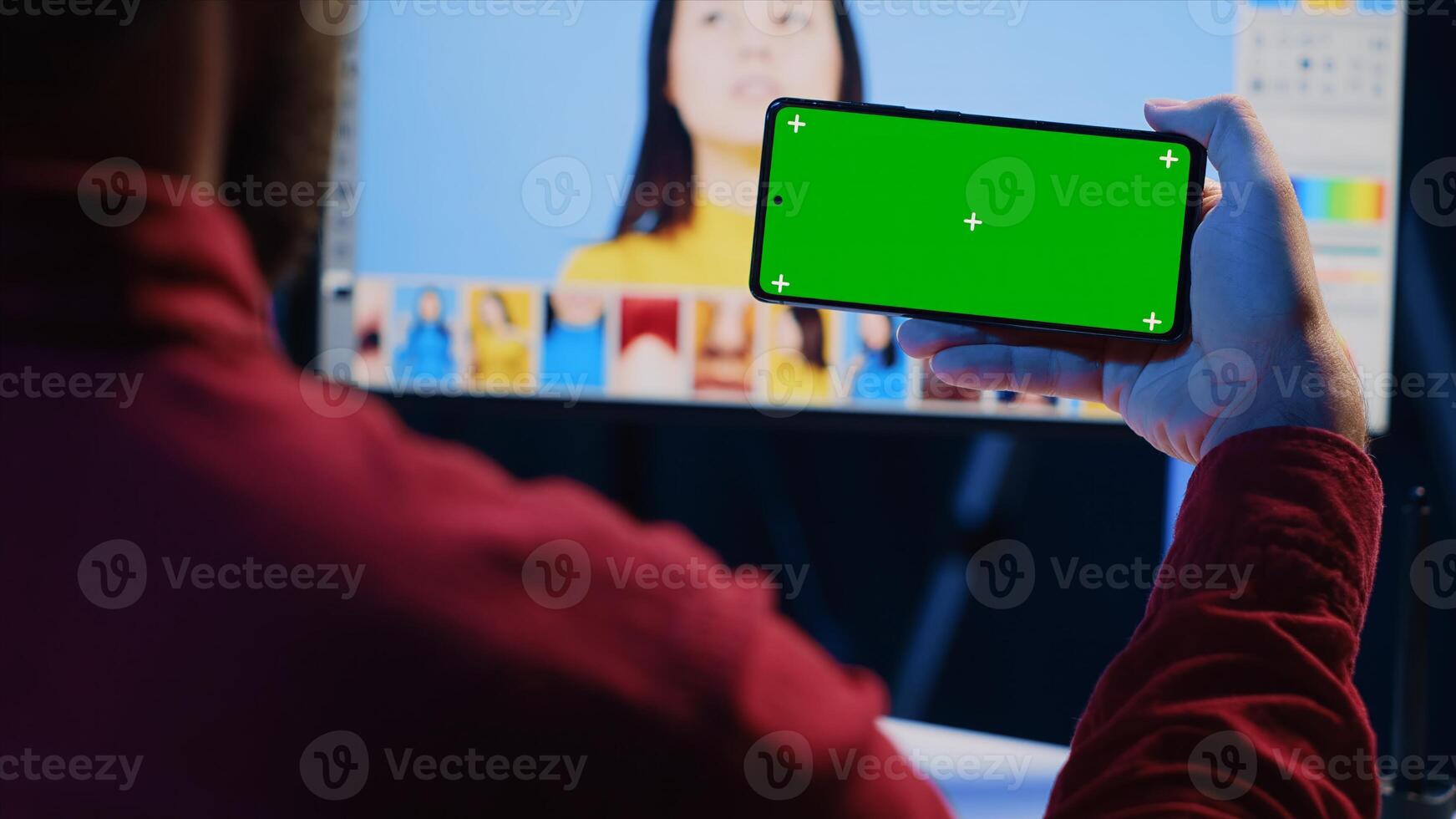 Photo editor using green screen mobile phone to watch tutorial, learning to color correct photographs in creative studio. Photographer watching guiding on chroma key smartphone