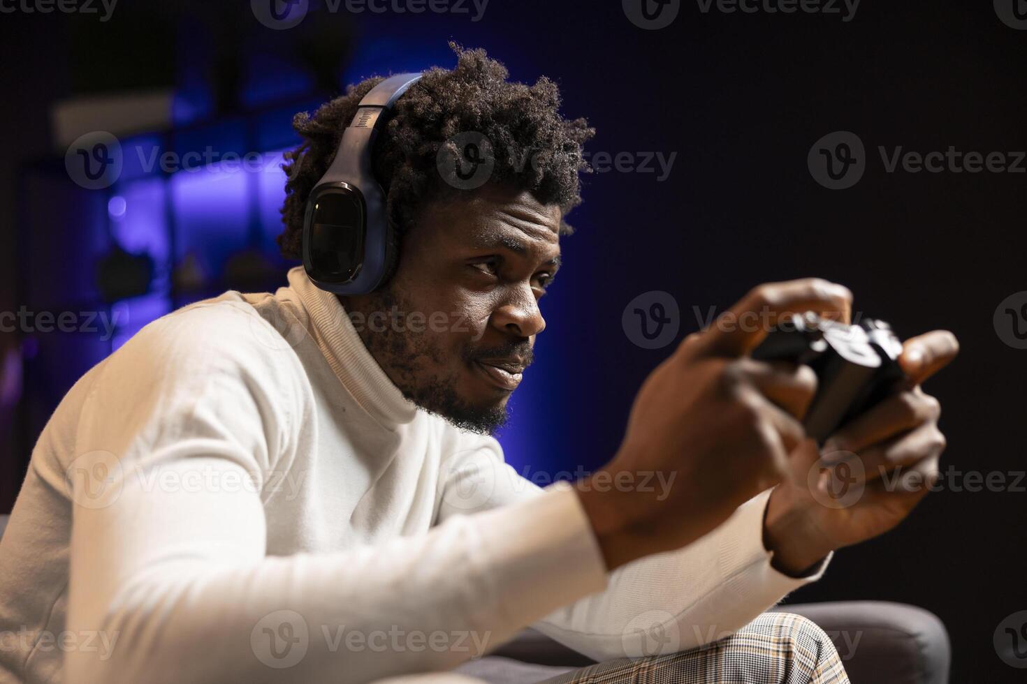Man playing shooter videogame in blue neon lit room, holding controller. Gamer participating in internet esports competition using professional gamepad and headphones for better victory chances photo