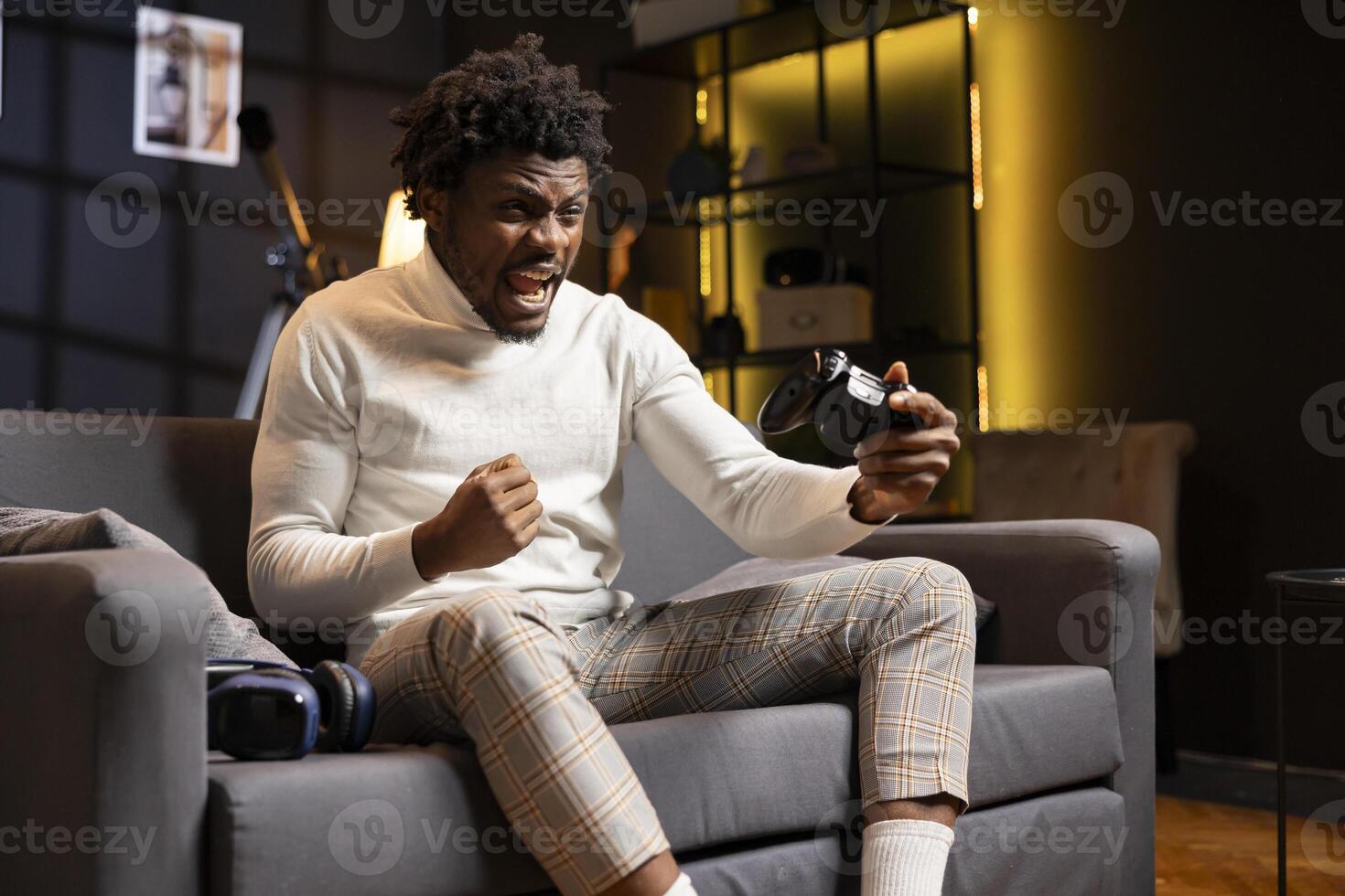Excited gamer screaming from joy after winning gaming console game in living room. Cheerful player bragging after being victorious in videogame, defeating all enemies using controller photo