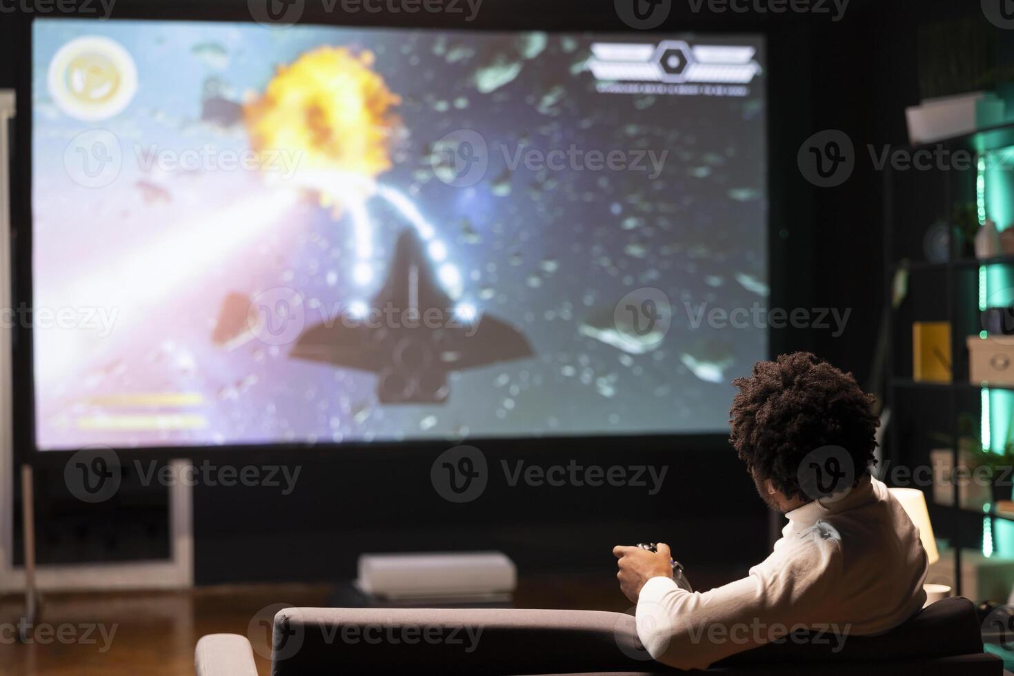 Man playing entertaining spaceship flying videogame on large smart TV, relaxing after long day at work. Player enjoying SF arcade game on gaming console, piloting spacecraft in galaxy using gamepad photo