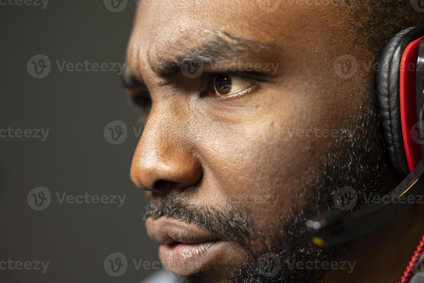 African american gamer feeling sad after losing online multiplayer action videogame match while talking on headphones with teammates. Close up shot of dejected man at game over message on monitor photo