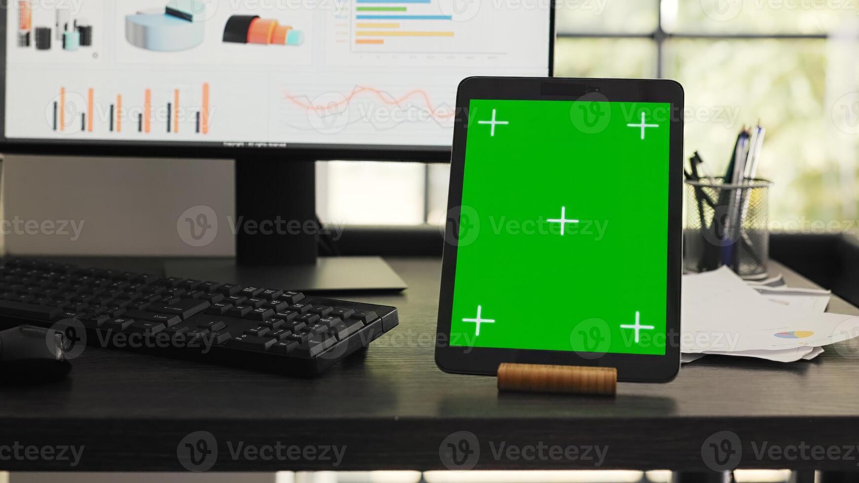 Desk with greenscreen on modern tablet in business coworking space, showing isolated chromakey layout design on mobile gadget display. Empty office workstation running device with copyspace. photo