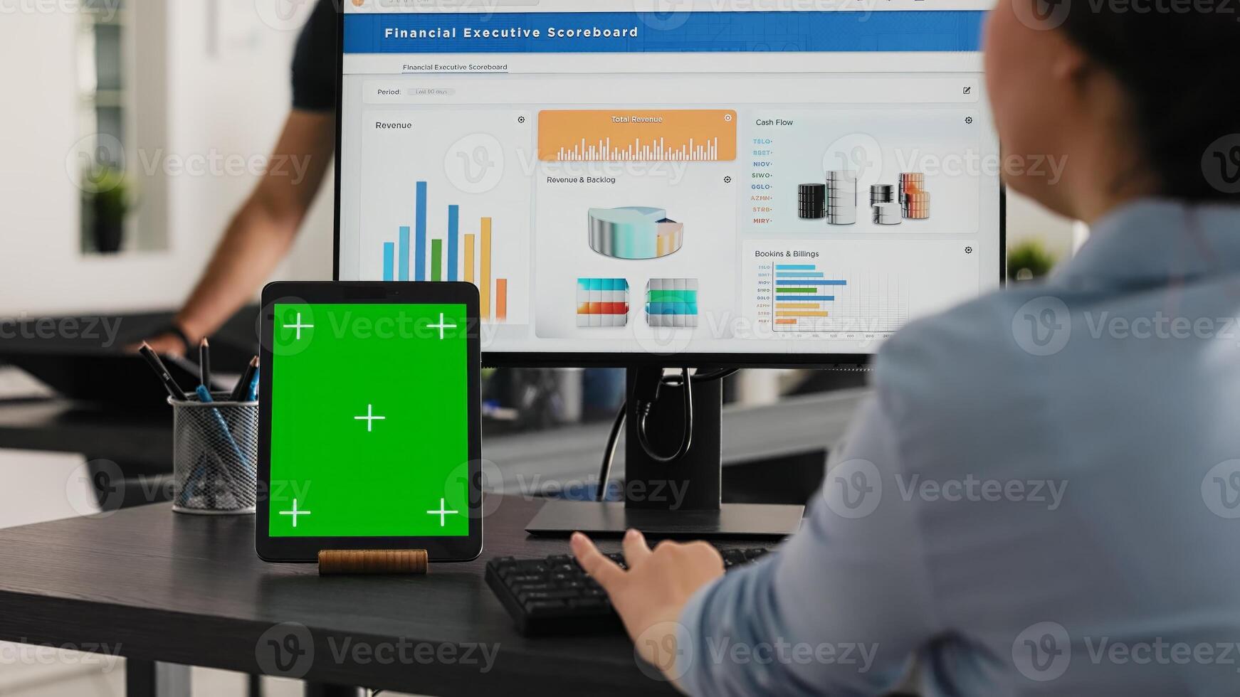 Specialist works with greenscreen tablet in open floor plan office, presenting isolated display on modern device. Businesswoman using pc monitor and blank chromakey layout on mini screen. photo