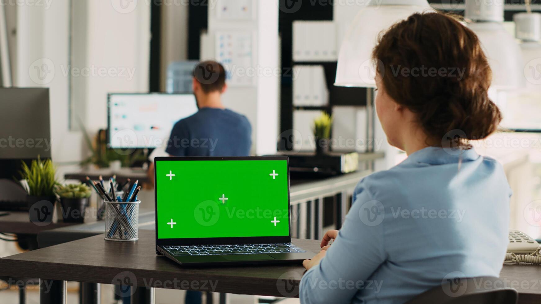 Team leader analyzes greenscreen display on laptop, working on business operations in open floor plan office. Employee using portable computer with blank mockup copyspace on pc. photo