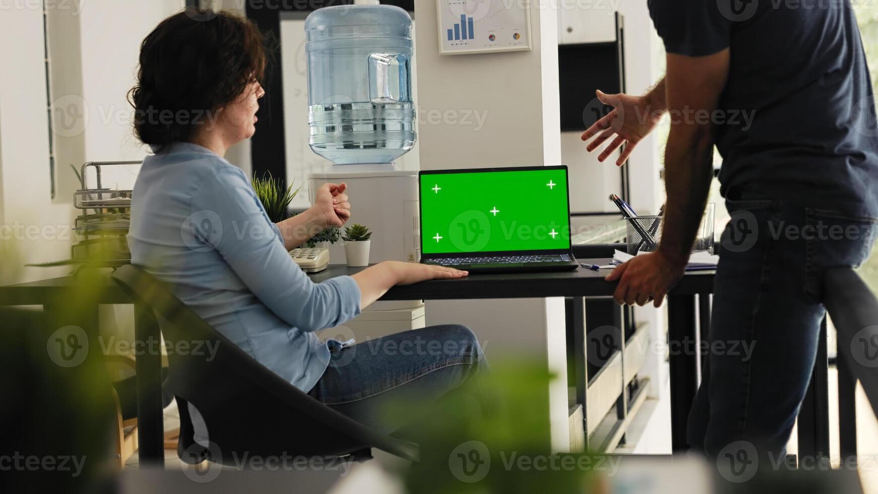 Business team review greenscreen display in coworking space office, brainstorming ideas for startup development, blank mockup template. Colleagues use laptop with chromakey screen. Handheld shot. photo