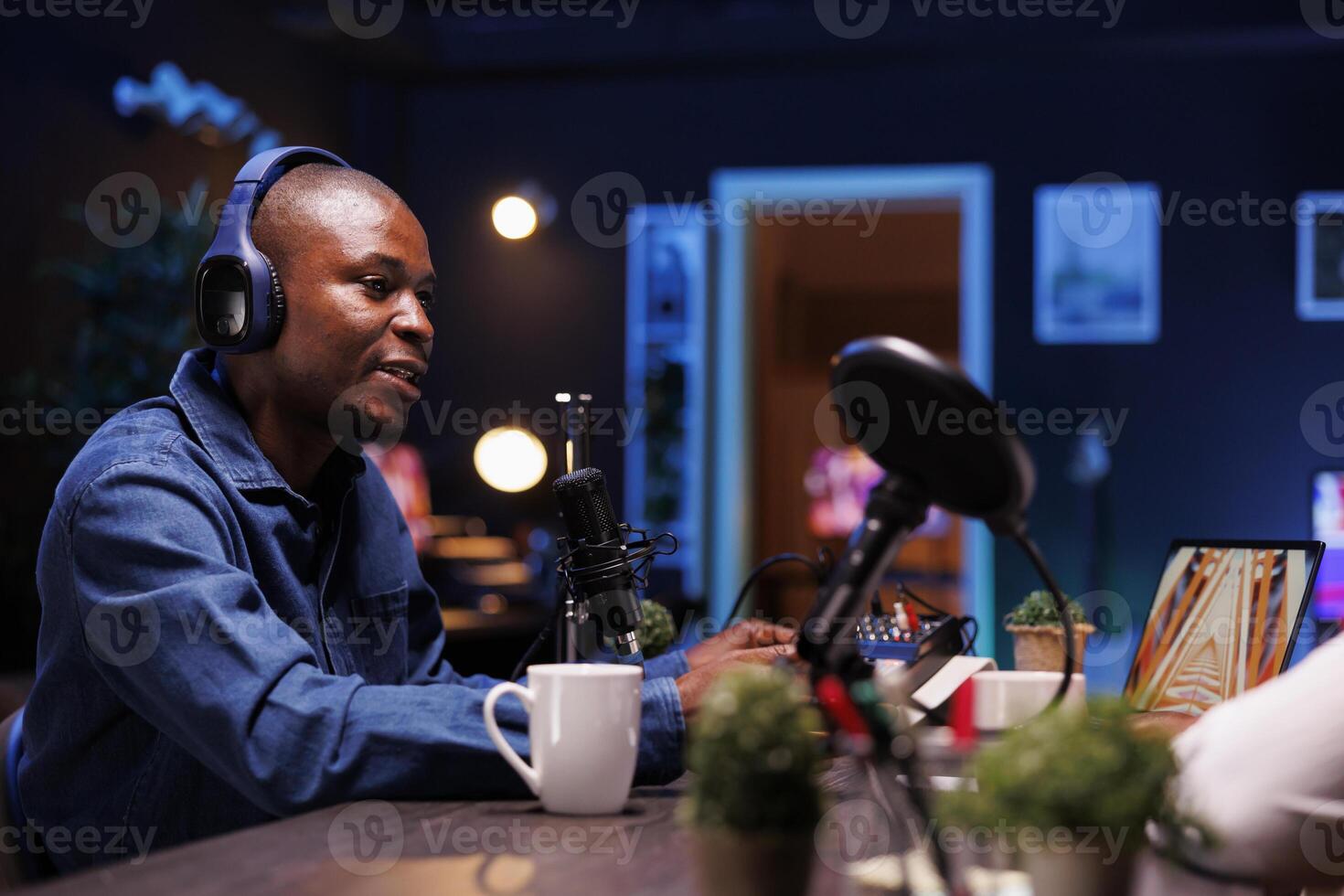 African American man moderating online discussions while speaking into a microphone while wearing headphones. Male content creator broadcasting a live talk show on podcast equipment. photo